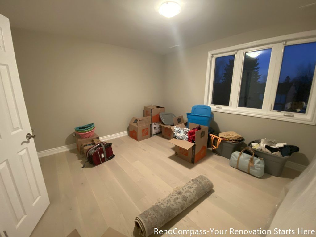 This completed bedroom renovation features newly installed light wood flooring, soft neutral wall tones, and a clean ceiling light layout that enhances brightness throughout the room. The large window brings in natural light, creating a calm and comfortable environment suitable for both rest and flexible daily use. Designed and completed by Reno Compass, the space prioritizes simplicity, functionality, and long-term livability.