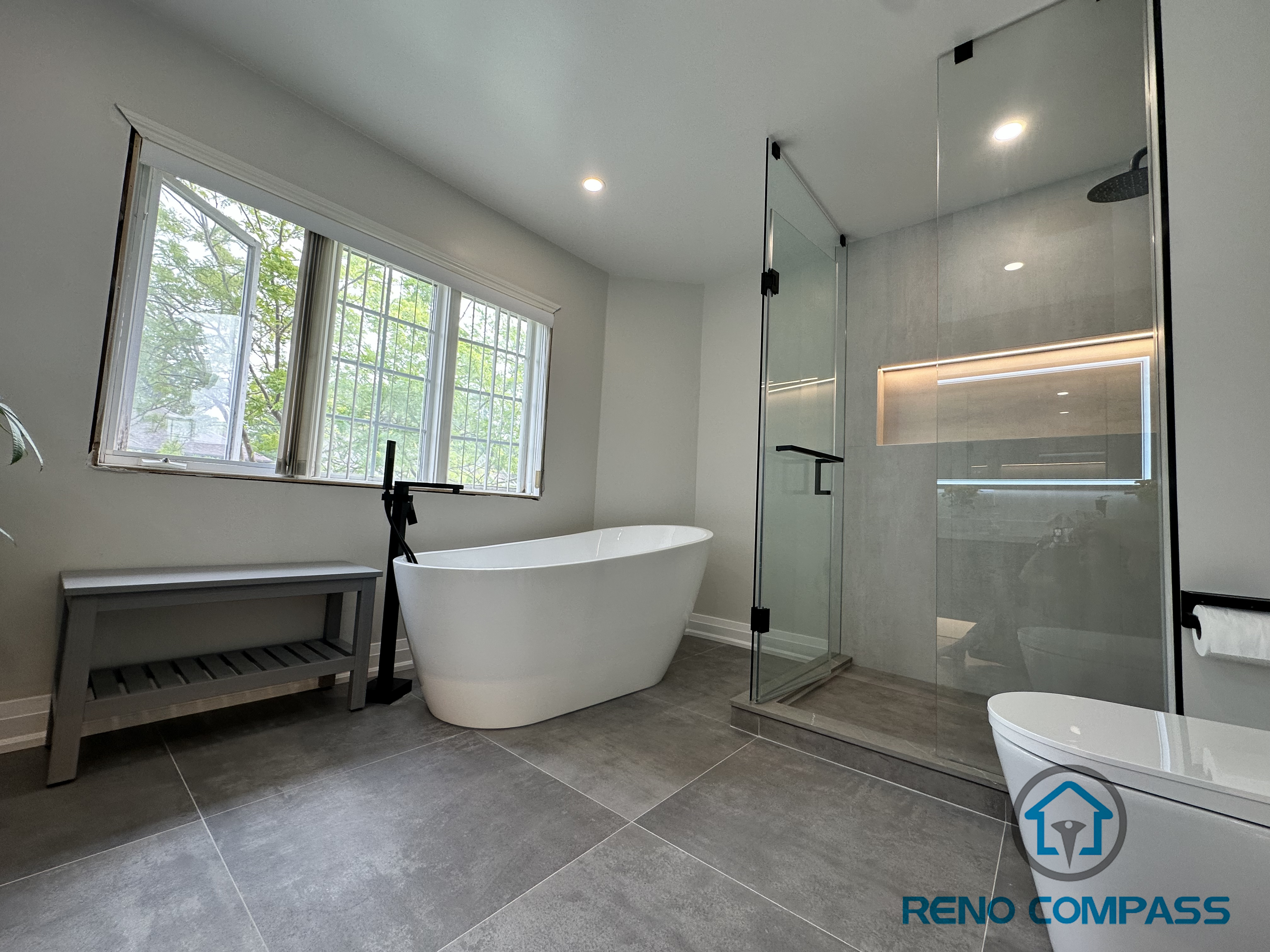 A luxurious Oakville bathroom featuring a spacious walk-in shower with frameless glass and a built-in niche, paired with a freestanding bathtub. This layout balances open design with functional storage, creating a spa-like retreat perfect for relaxation and everyday use.