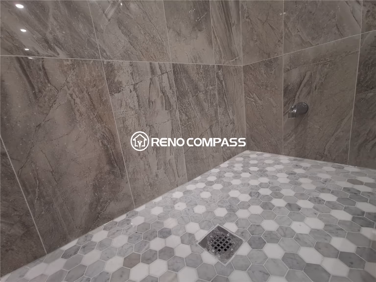 This Markham basement renovation features a modern walk-in shower with marble-look porcelain wall tiles and hexagon mosaic shower flooring designed for slip resistance and visual texture. The detailed tile installation enhances both durability and aesthetics while ensuring proper waterproofing for long-term basement bathroom use. Neutral tones and precise grout lines create a clean, contemporary finish suited for modern homes. Completed by a professional Toronto renovation company, this project highlights expert tile work, quality waterproofing, and functional bathroom design tailored for basement renovations across the Greater Toronto Area.