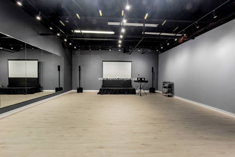 A spacious commercial studio renovation featuring luxury vinyl plank flooring, full-length mirrors, and professional track lighting. This Richmond Hill project showcases a modern industrial aesthetic with an exposed black ceiling, perfect for music schools and dance studios.