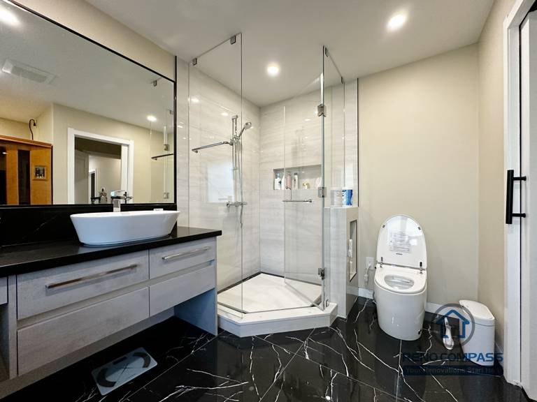 Modern bathroom completed as part of a North York interior renovation. This space features a frameless glass shower, large-format wall tiles, black marble-look flooring, and a custom vanity with vessel sink. Designed for durability, comfort, and clean visual balance by a professional Toronto renovation company.