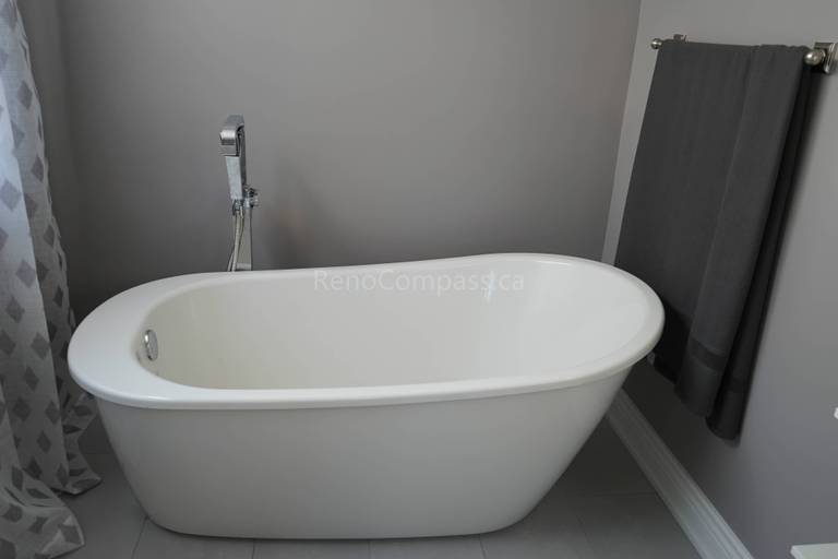 This Markham bathroom renovation showcases a sleek freestanding bathtub paired with modern fixtures and neutral wall tones. The minimalist design creates a spa-like atmosphere, offering homeowners a relaxing and elegant bathing space while enhancing the overall value and comfort of the home.