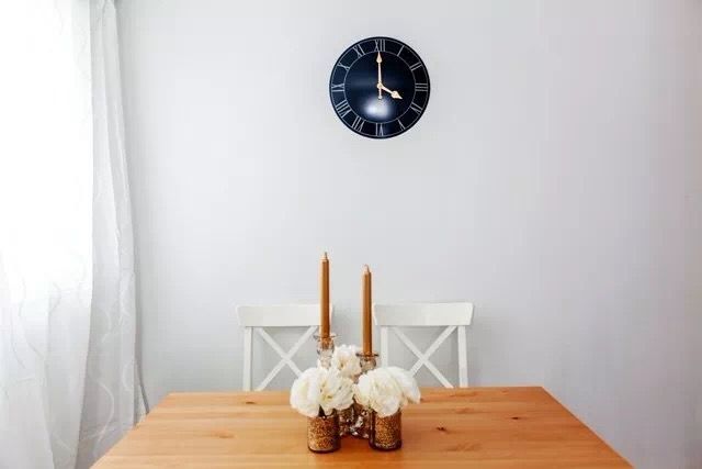 This Toronto interior renovation highlights a clean and elegant dining area with minimalist styling. Featuring a natural wood dining table, decorative candle centerpiece, and modern wall clock, the space reflects simplicity and warmth. Soft natural lighting and neutral tones enhance the overall ambiance, creating a refined and functional dining environment.
