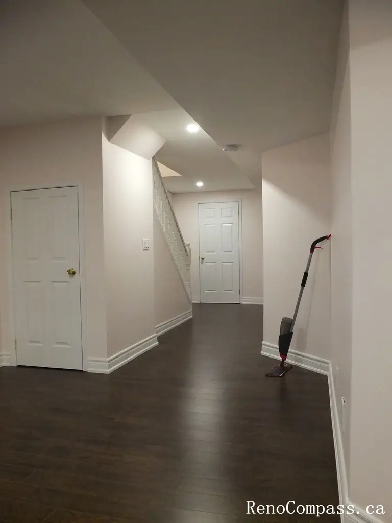 Professional basement renovation in Newmarket featuring an extended corridor layout, recessed ceiling lighting, clean white doors and trim, and rich dark hardwood flooring. This lower-level upgrade was completed by an experienced Toronto Renovation Company to maximize space flow and improve overall functionality.
