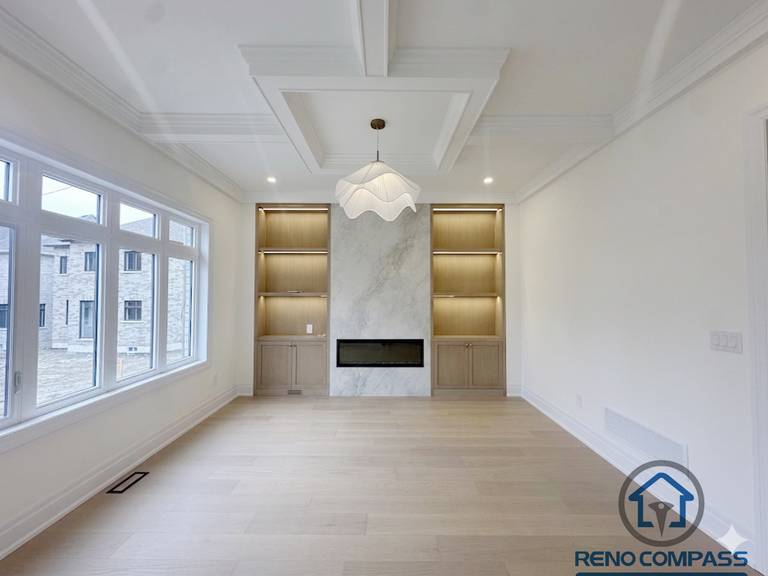 Bright living room in a Toronto new home upgrade featuring a modern fireplace wall, built-in shelving, and a coffered ceiling for added depth and symmetry.