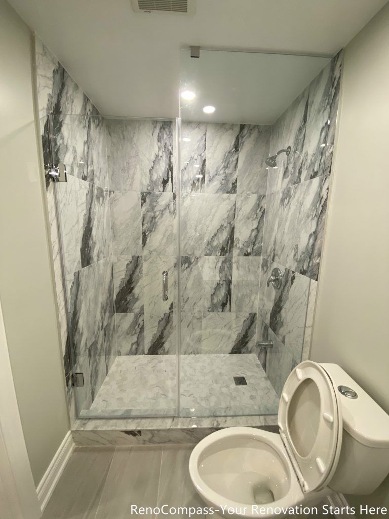 This Richmond Hill basement bathroom renovation showcases a modern walk-in glass shower with full-height marble-style wall tiles and sleek contemporary finishes. Designed and completed by professional Toronto renovation company Reno Compass Inc., the space combines functionality and luxury in a compact layout. The upgraded shower system, clean tile installation, and bright lighting create a comfortable and high-end bathroom ideal for basement living or rental use.