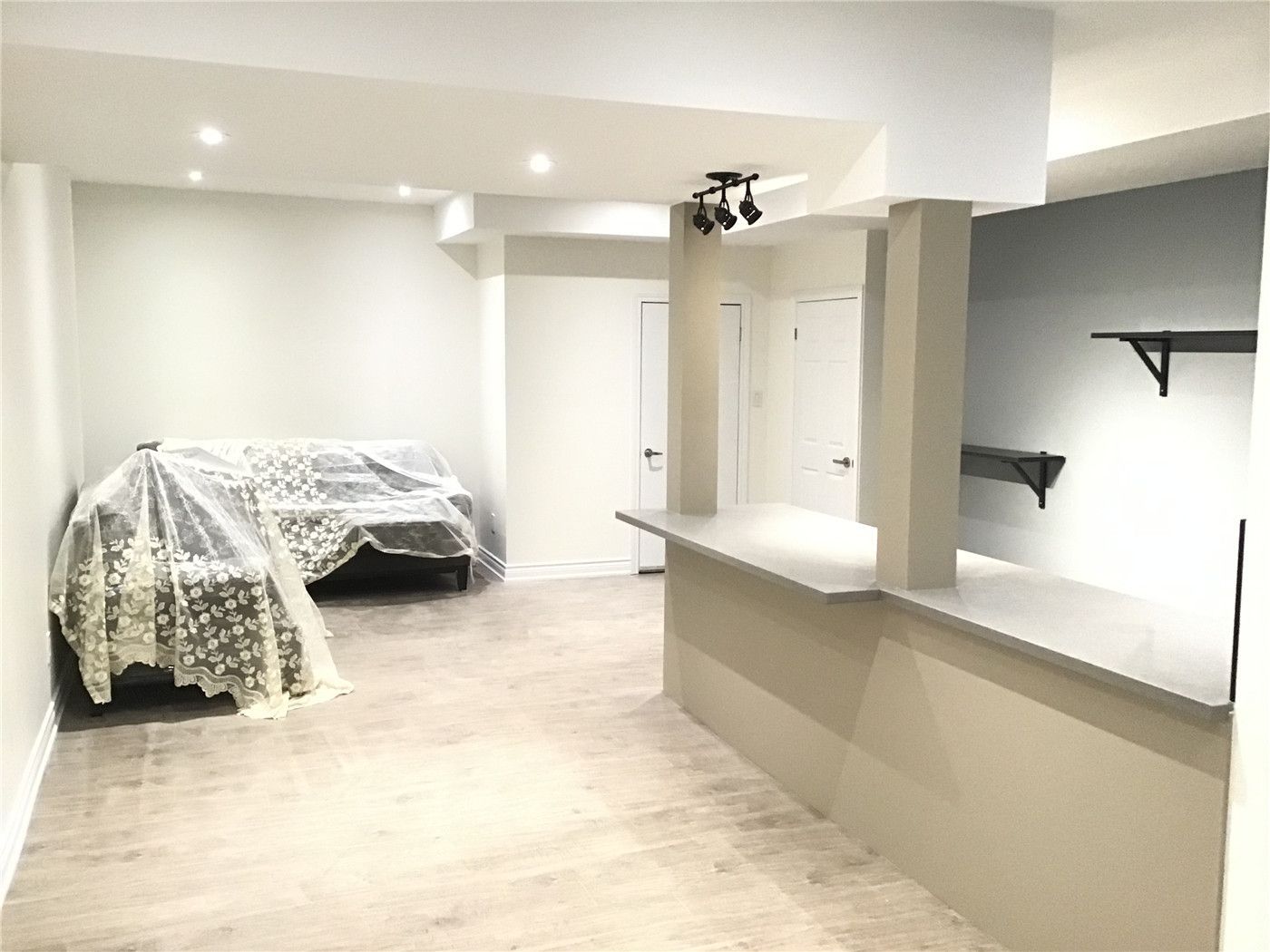 This Aurora basement renovation showcases a spacious open-concept layout with durable vinyl flooring, modern recessed lighting, and a built-in counter feature. The flexible design allows the space to function as a living area, bedroom, or entertainment zone, offering both comfort and practicality for a finished basement.