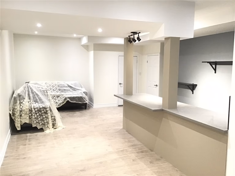 This Aurora basement renovation showcases a spacious open-concept layout with durable vinyl flooring, modern recessed lighting, and a built-in counter feature. The flexible design allows the space to function as a living area, bedroom, or entertainment zone, offering both comfort and practicality for a finished basement.
