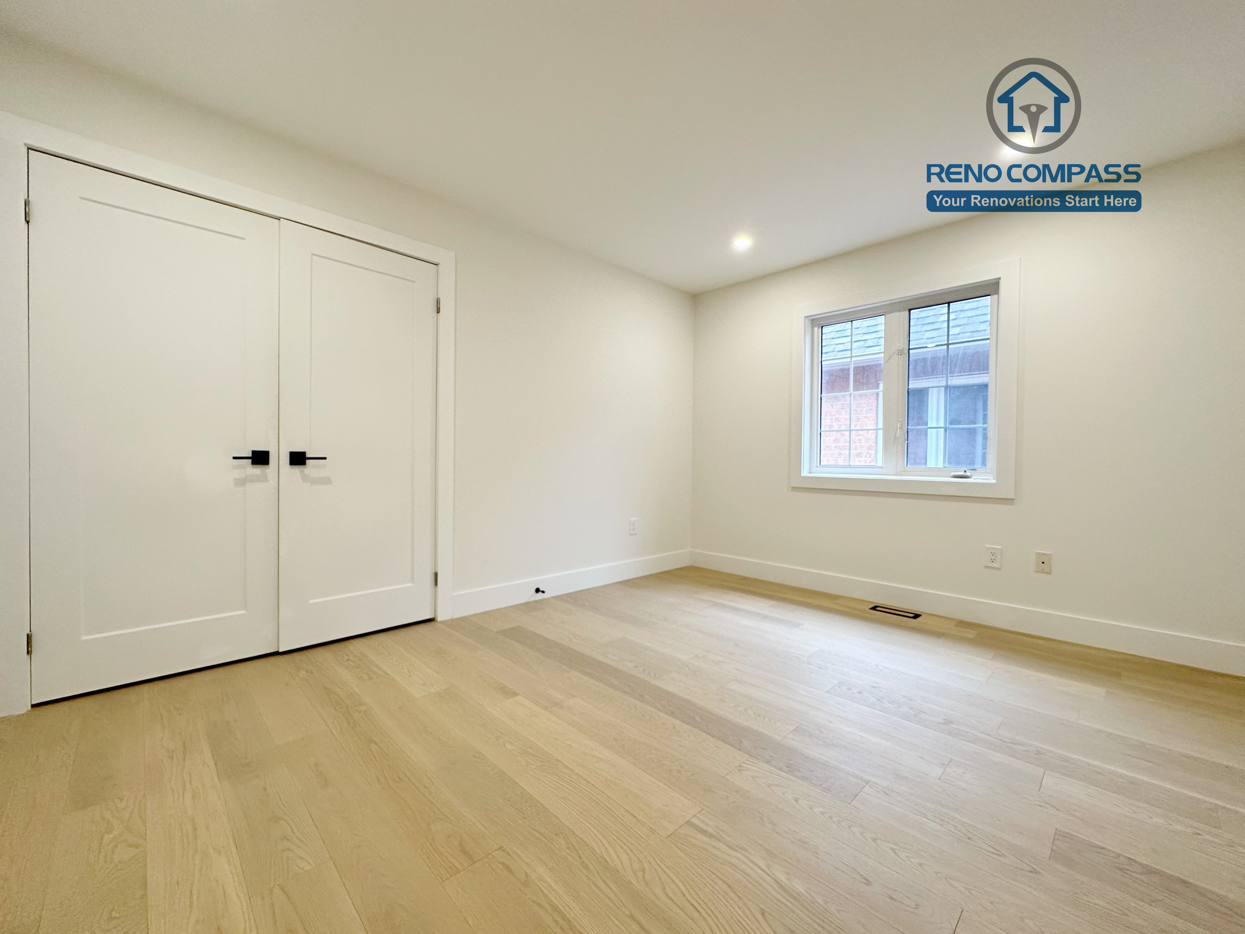 Minimalist bedroom in a Richmond Hill home featuring newly installed light-tone hardwood flooring, clean white walls, recessed lighting, and custom closet doors for a bright and functional interior.