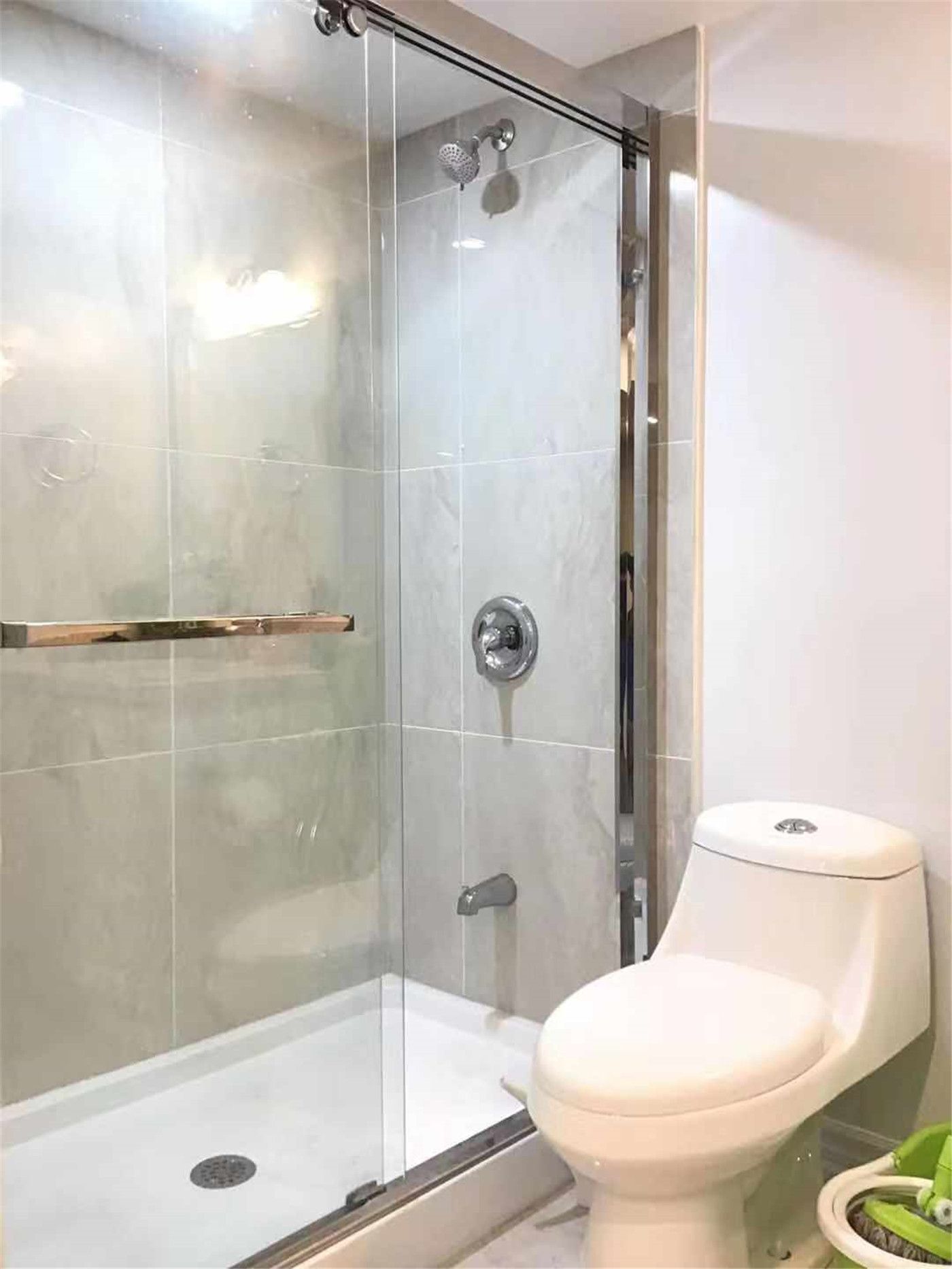 This Scarborough basement renovation showcases a sleek bathroom design featuring a frameless glass shower enclosure, modern rainfall shower system, and a space-saving toilet. The clean tile finish and efficient layout maximize both comfort and functionality, making it ideal for basement living. Completed by a trusted Toronto Renovation Company, this project highlights practical design with a contemporary touch.