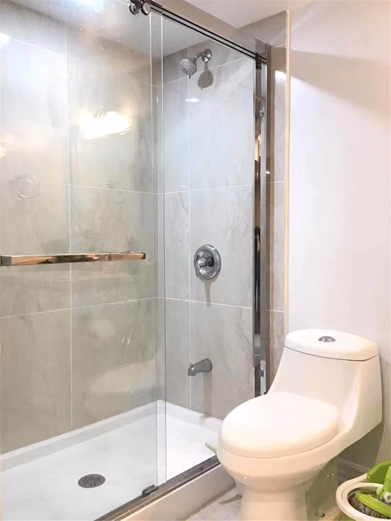 This Scarborough basement renovation showcases a sleek bathroom design featuring a frameless glass shower enclosure, modern rainfall shower system, and a space-saving toilet. The clean tile finish and efficient layout maximize both comfort and functionality, making it ideal for basement living. Completed by a trusted Toronto Renovation Company, this project highlights practical design with a contemporary touch.