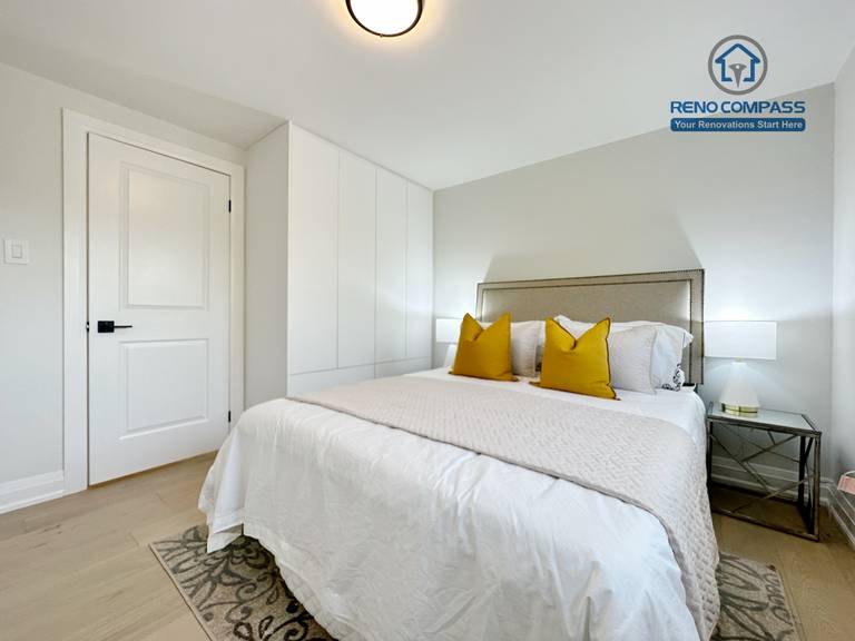 This Richmond Hill interior renovation features a modern bedroom with custom wall paneling, built-in storage, light hardwood flooring, and a calm neutral color palette. Thoughtful lighting and staged furnishings create a comfortable and relaxing atmosphere. Completed by a Toronto renovation company, the design enhances both functionality and everyday living comfort.
