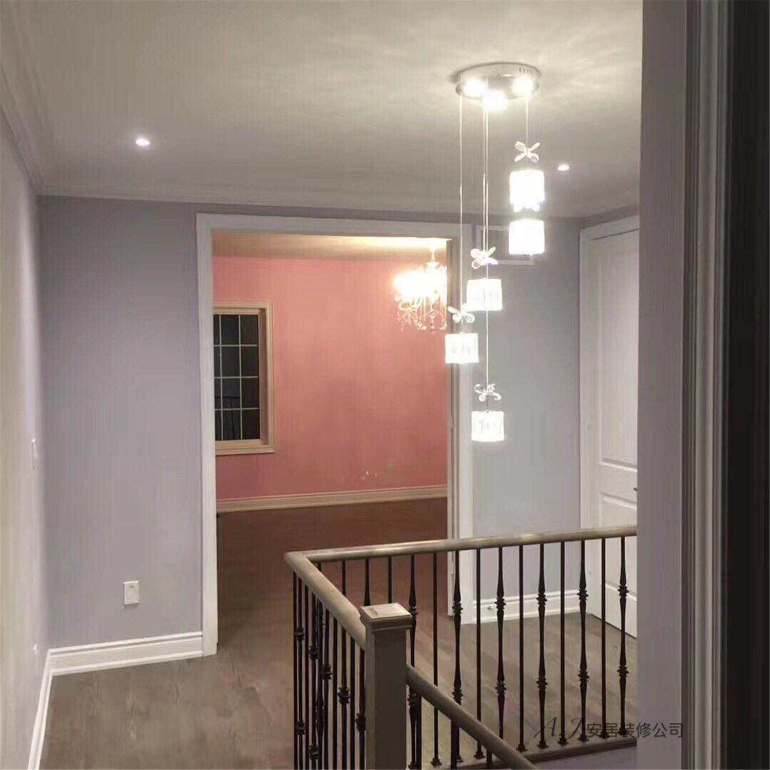 This Scarborough interior renovation features a stylish staircase landing with modern pendant lighting that adds elegance and visual height to the space. Soft grey walls, white trim details, and warm wood flooring create a clean and contemporary hallway design. The open layout connects the staircase with adjacent rooms, while the decorative hanging light fixture provides a refined focal point that enhances the overall interior renovation in this Scarborough home.