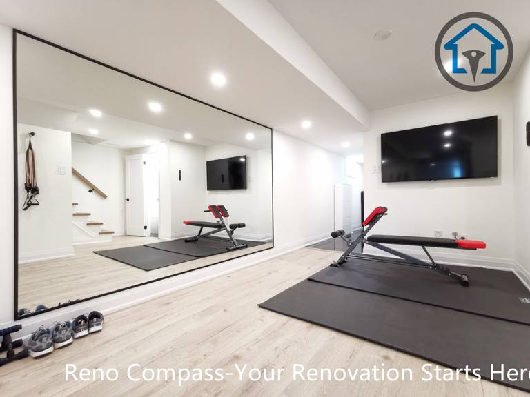 This North York basement renovation transforms the space into a modern home gym featuring a full mirror wall, recessed ceiling lighting, and durable light-tone flooring. The open layout improves brightness and functionality, creating a clean and versatile workout area completed by a Toronto renovation company focused on practical design and high-quality finishing.