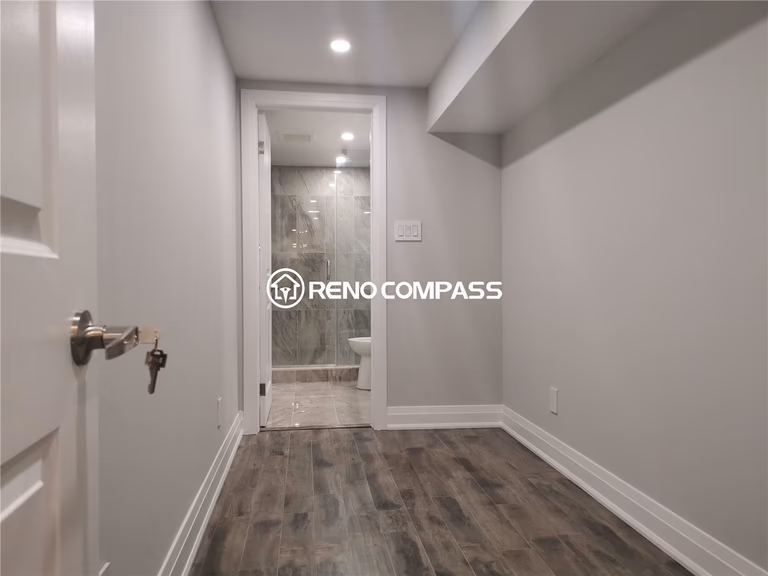 This Markham basement renovation showcases a newly finished bedroom area with waterproof vinyl plank flooring, recessed pot lighting, and a clean modern layout leading to a fully upgraded bathroom. The neutral wall tones and durable flooring create a comfortable, low-maintenance living space ideal for extended family use or rental potential. Careful finishing details, including baseboards and lighting, enhance both functionality and visual appeal. Completed by a professional Toronto renovation company, this basement upgrade highlights quality craftsmanship and practical design tailored for modern homes in the Greater Toronto Area.