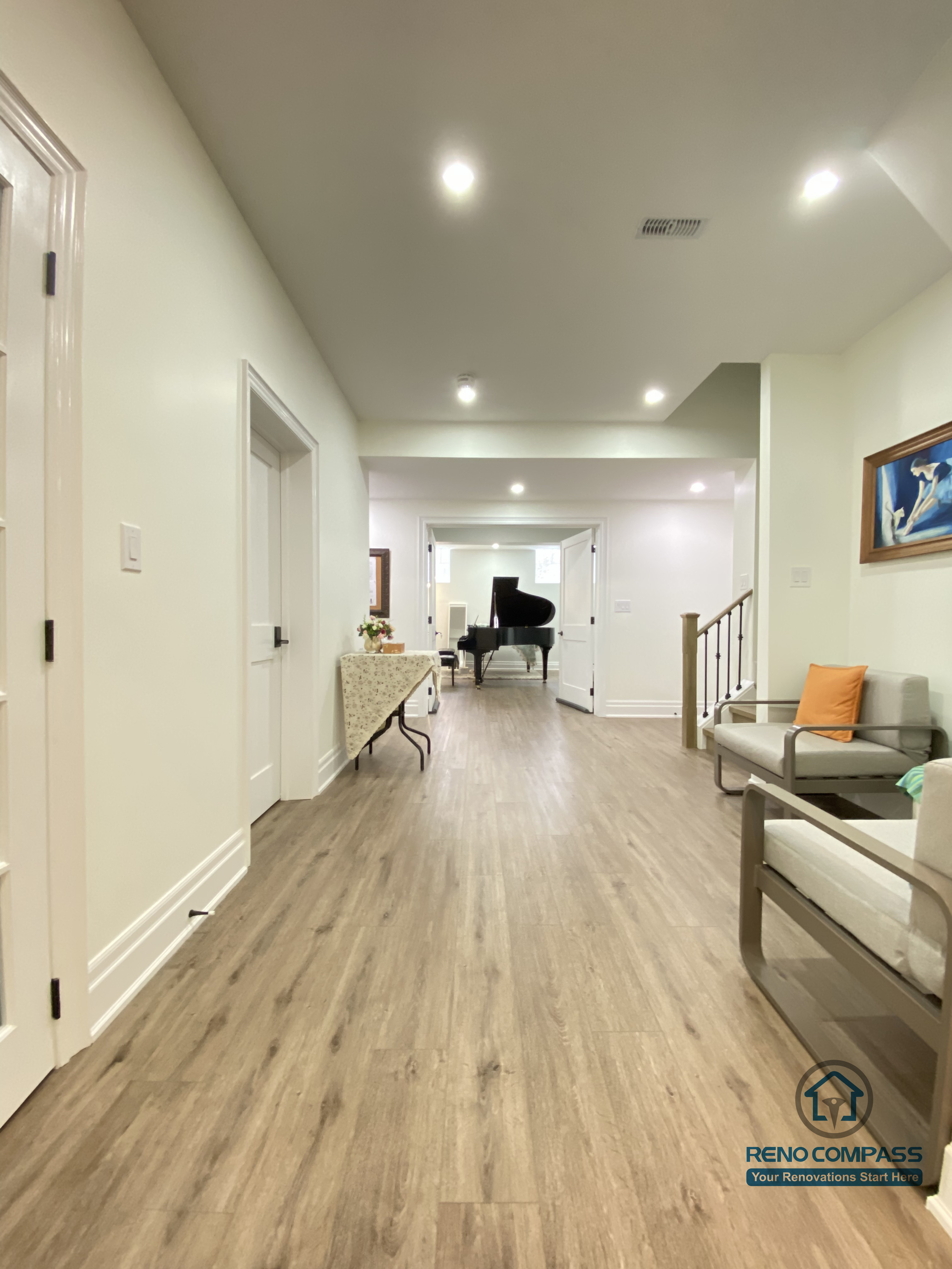 This Oakville basement renovation highlights a spacious, well-lit hallway that connects multiple functional areas with a clean and cohesive flow. Continuous wood flooring enhances visual depth, while recessed ceiling lights and glass-panel doors maintain brightness and openness throughout the space. Minimal furnishings and neutral finishes help define circulation without clutter. As a professional Toronto renovation company, Reno Compass designs basement layouts that prioritize movement, natural light distribution, and everyday comfort, creating lower-level spaces that feel open, organized, and inviting.