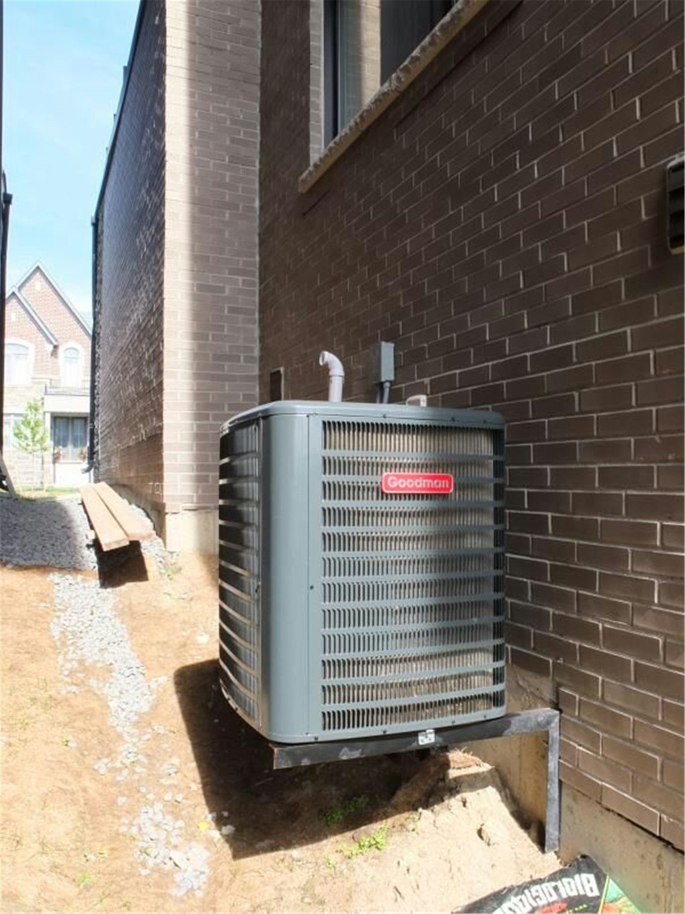 Professional outdoor air conditioner condenser installation by Reno Compass in Toronto. This energy-efficient HVAC unit is securely mounted on a raised stand with proper drainage and ventilation clearance, ensuring optimal cooling performance, durability, and safe operation for residential homes. Installed by licensed technicians for long-term reliability and comfort.