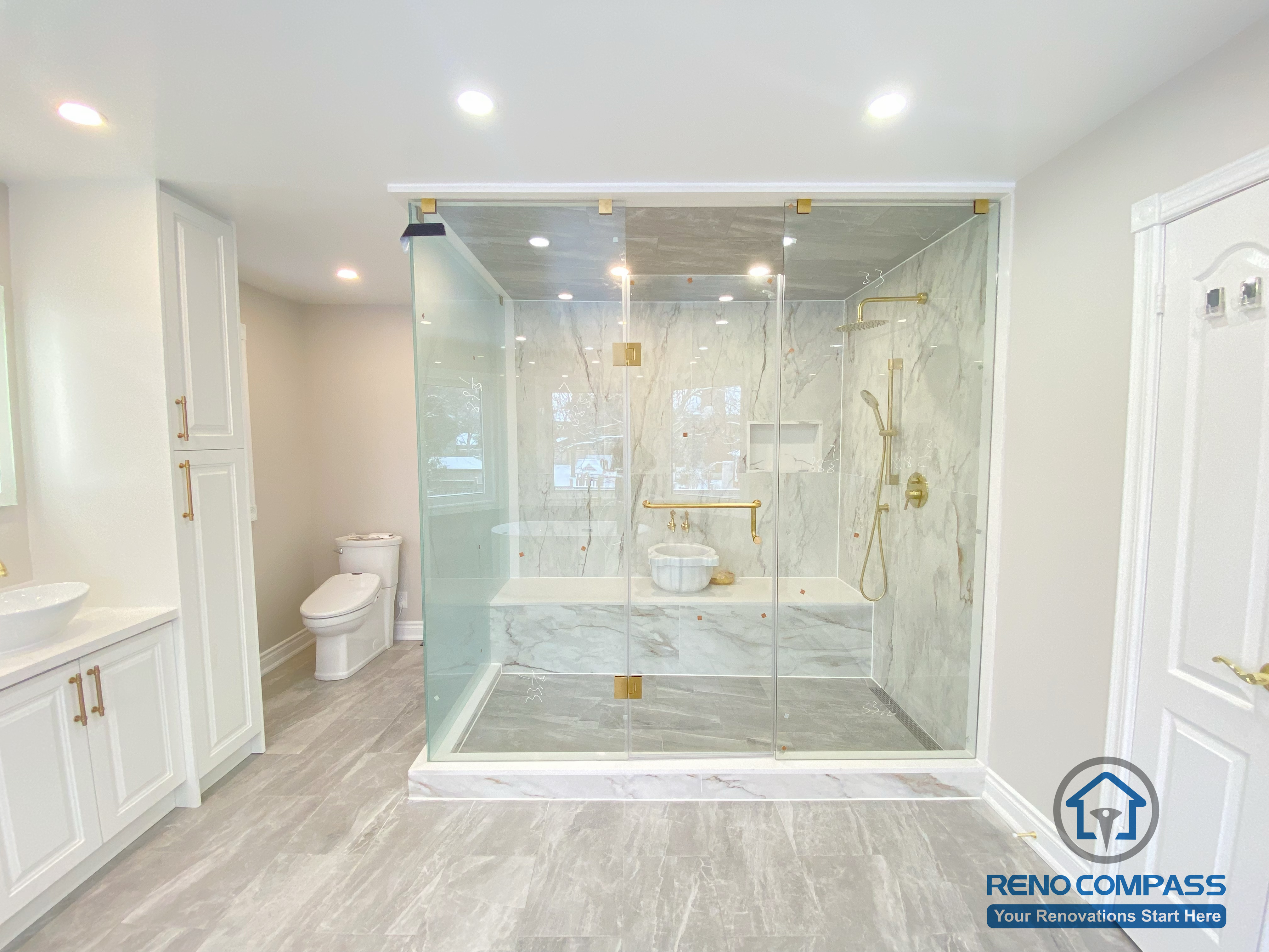 This Richmond Hill bathroom renovation showcases a bright and elegant design featuring a frameless glass shower enclosure, built-in bathtub, marble-style wall tiles, and gold-finish fixtures. The custom white vanity with integrated lighting mirror and large-format floor tiles enhance both functionality and visual openness. This project reflects high-quality craftsmanship and thoughtful layout planning for a modern bathroom renovation in Richmond Hill.
