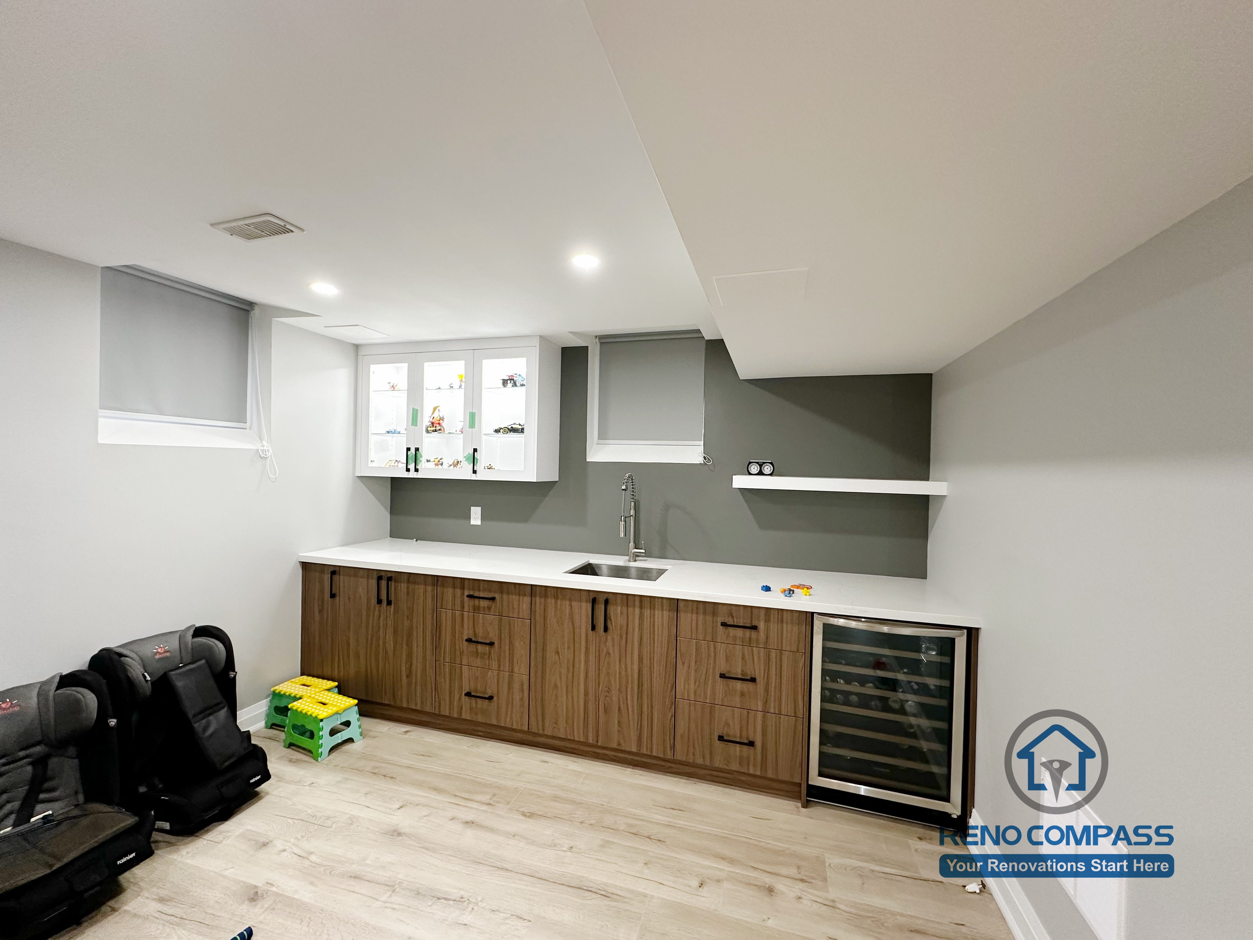 This Newmarket basement renovation features a custom wet bar with wood-tone cabinetry, quartz countertop, and an integrated beverage fridge. Designed for entertaining and family use, the finished basement bar area includes modern lighting, functional storage, and a clean contemporary layout that enhances the overall basement living space.
