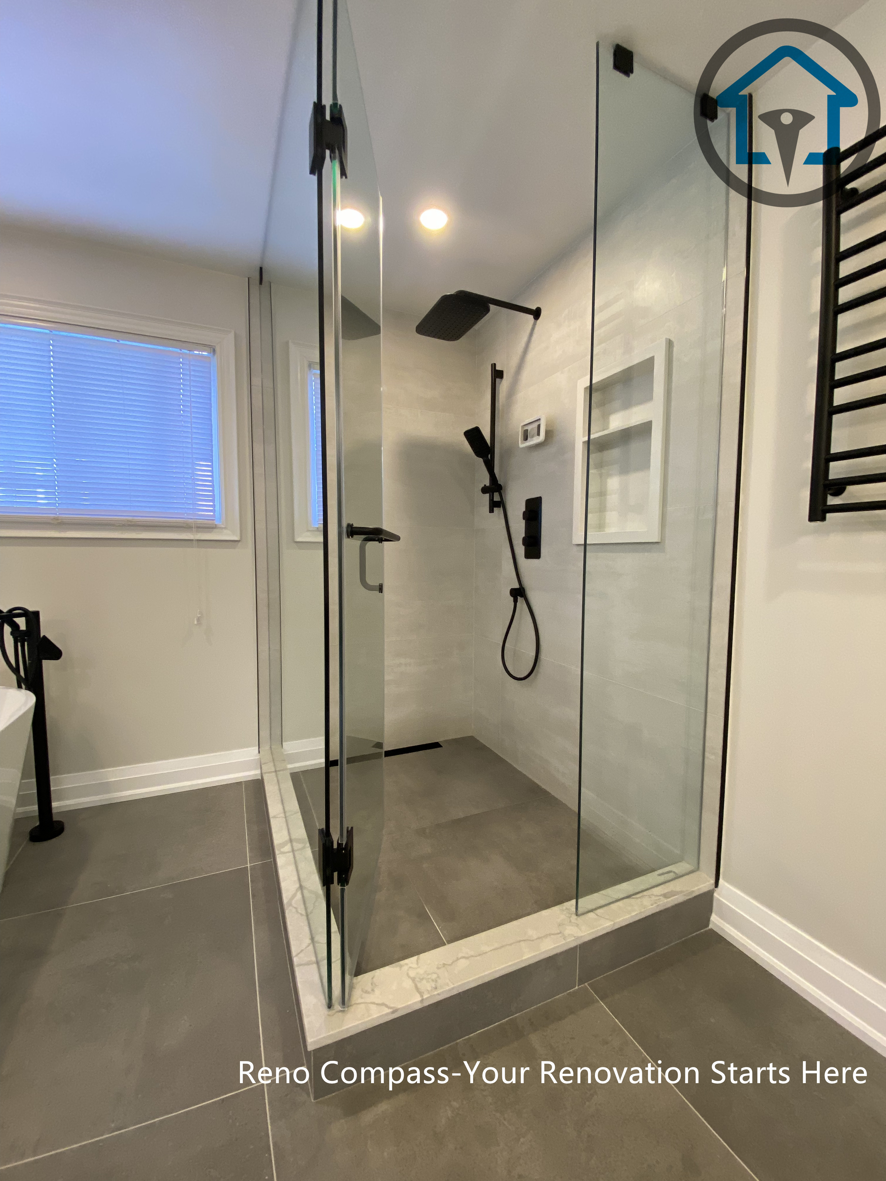 Spacious bathroom renovation in Markham featuring a frameless glass walk-in shower, freestanding soaking tub, large-format floor tiles, and modern matte black fixtures. The layout emphasizes comfort, functionality, and a clean contemporary aesthetic completed by a professional Toronto renovation company.