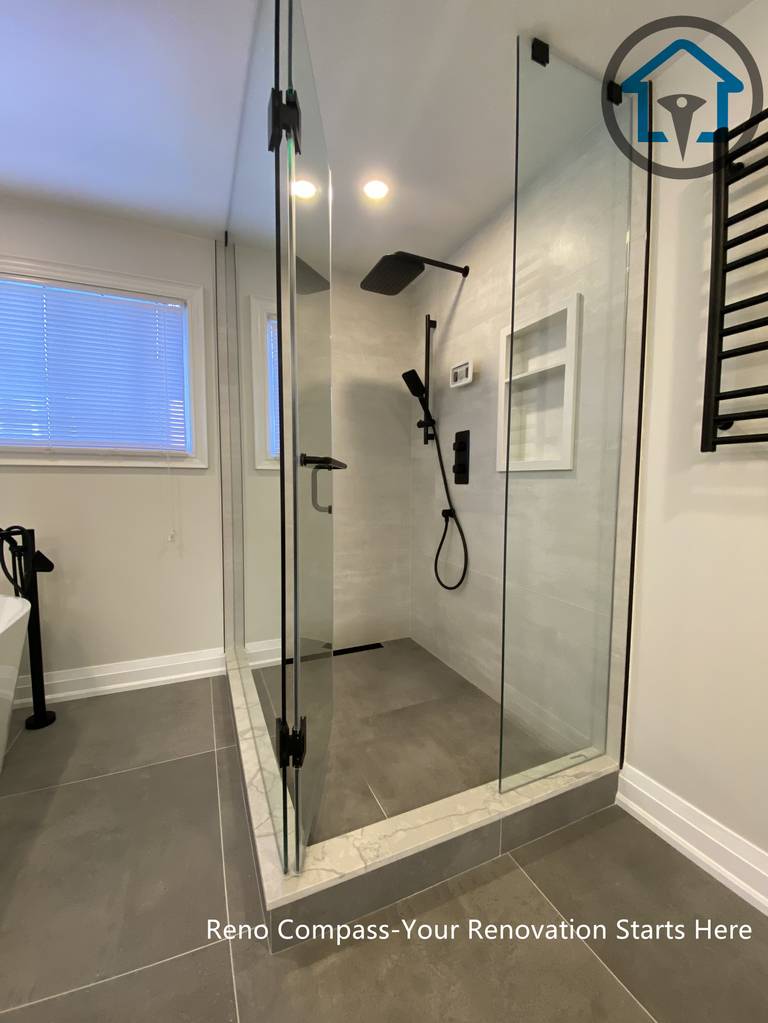 Spacious bathroom renovation in Markham featuring a frameless glass walk-in shower, freestanding soaking tub, large-format floor tiles, and modern matte black fixtures. The layout emphasizes comfort, functionality, and a clean contemporary aesthetic completed by a professional Toronto renovation company.