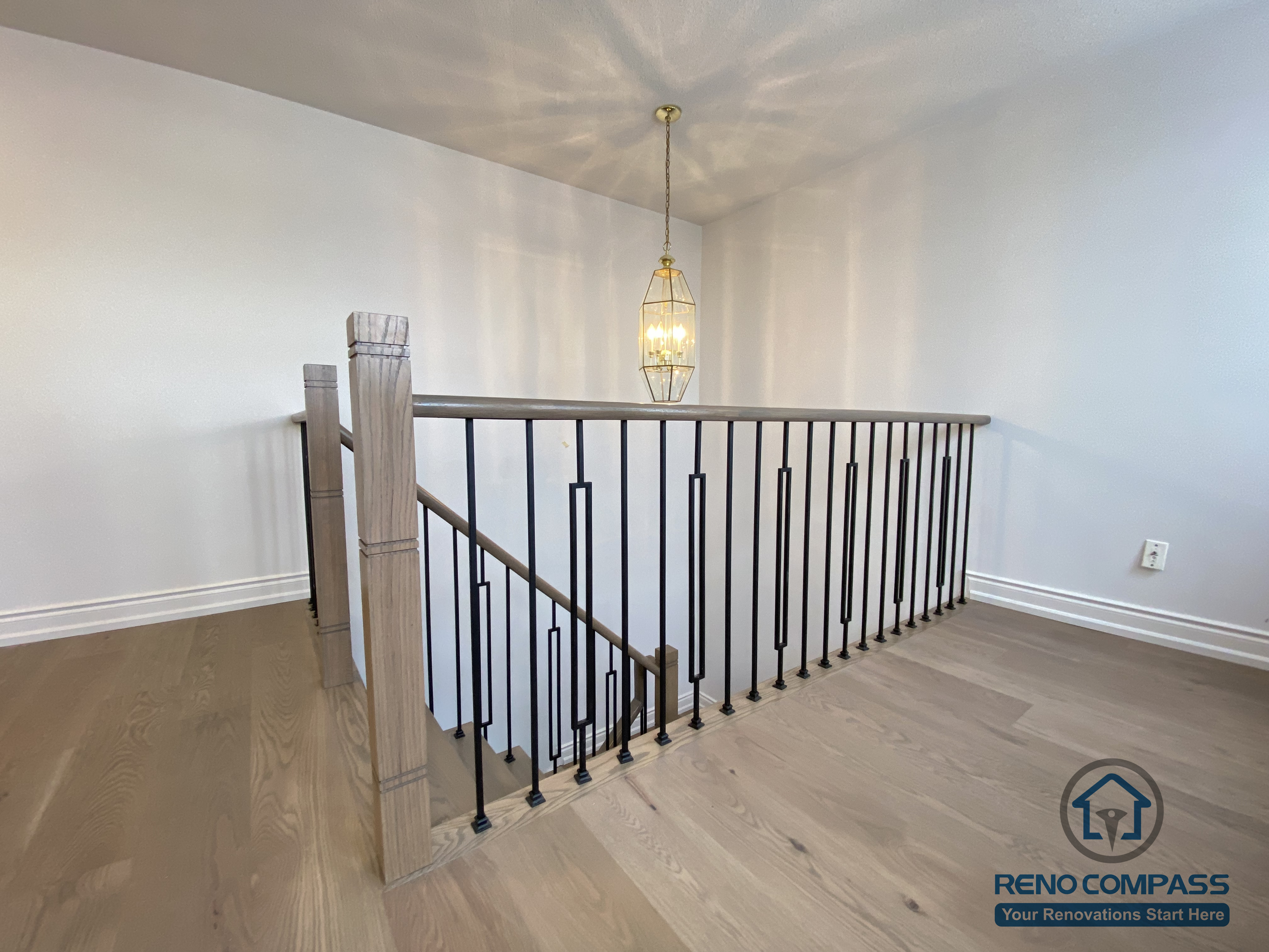 This staircase renovation in Markham showcases a refined transition space featuring custom black iron railings paired with engineered hardwood flooring. Clean vertical balusters and a solid wood handrail enhance safety while maintaining an open, modern visual connection between levels. The upper landing is finished with warm-toned hardwood, creating continuity with the rest of the home’s flooring and improving overall flow. Completed by a trusted Toronto renovation company, this staircase upgrade emphasizes proportion, durability, and timeless interior design suitable for long-term family living.