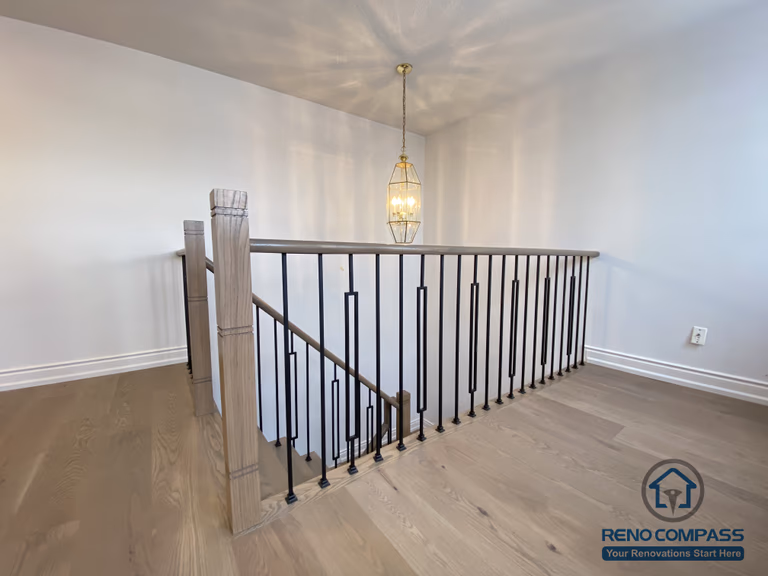 This staircase renovation in Markham showcases a refined transition space featuring custom black iron railings paired with engineered hardwood flooring. Clean vertical balusters and a solid wood handrail enhance safety while maintaining an open, modern visual connection between levels. The upper landing is finished with warm-toned hardwood, creating continuity with the rest of the home’s flooring and improving overall flow. Completed by a trusted Toronto renovation company, this staircase upgrade emphasizes proportion, durability, and timeless interior design suitable for long-term family living.