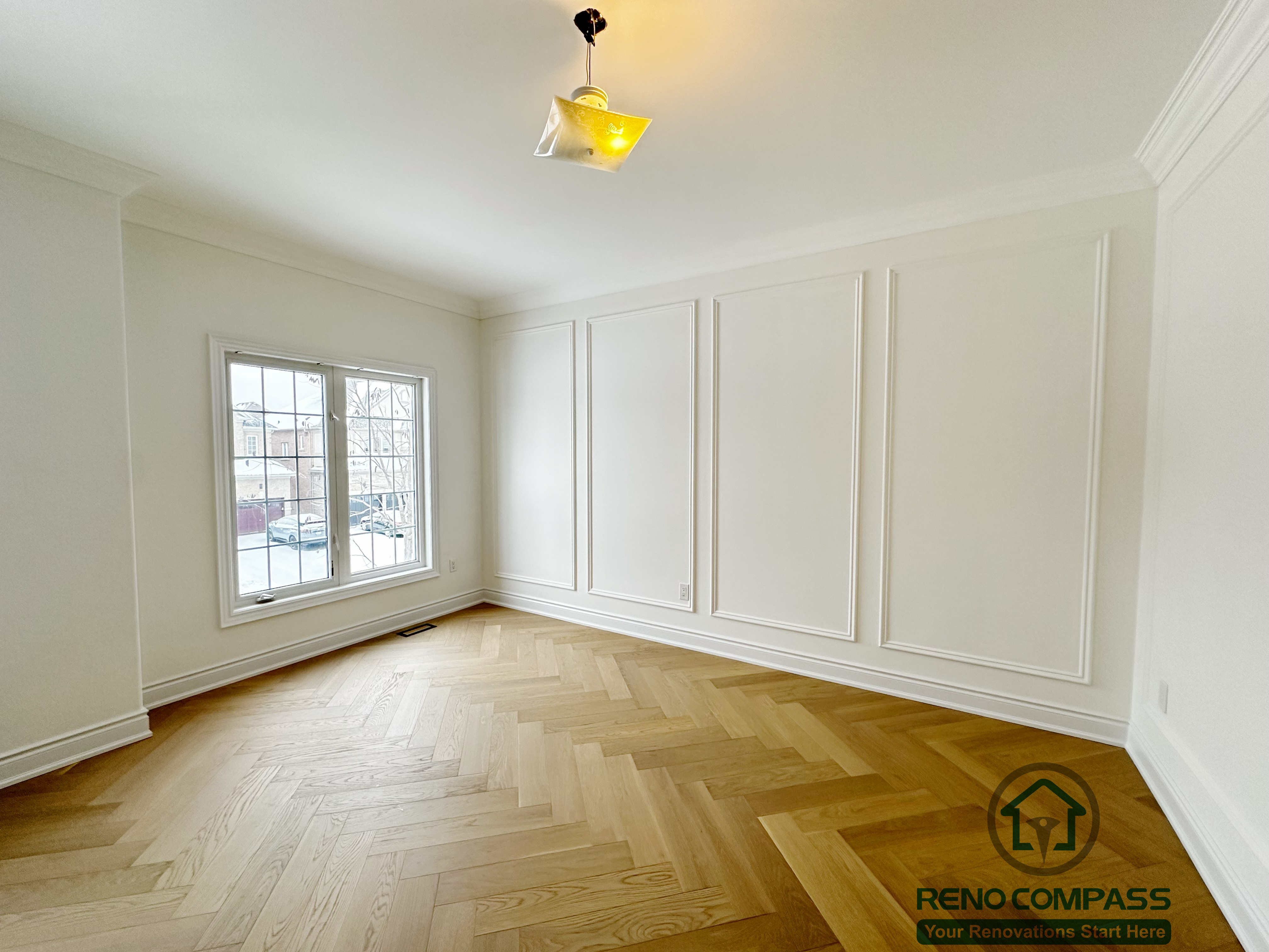 Refined hallway completed as part of a Vaughan interior renovation, featuring custom wall paneling, crown moulding, clean white finishes, and herringbone-pattern hardwood flooring. The balanced proportions and seamless detailing highlight the craftsmanship of a professional Toronto renovation company.