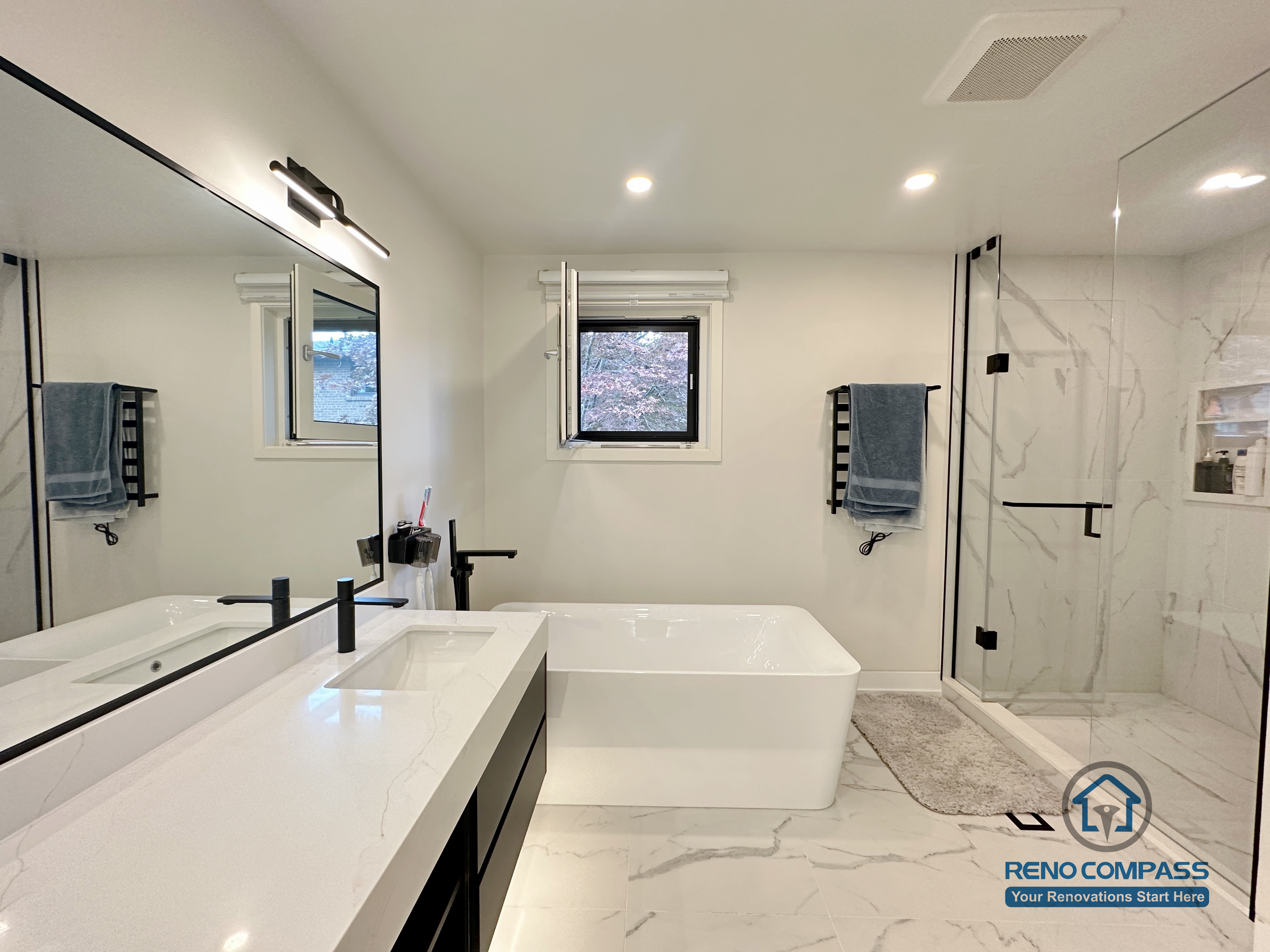 Bright and modern bathroom renovation in Toronto featuring a freestanding bathtub, frameless glass shower, marble-look porcelain tiles, custom vanity, and matte black fixtures. Designed and completed by a professional Toronto renovation company with attention to layout, lighting, and functionality.