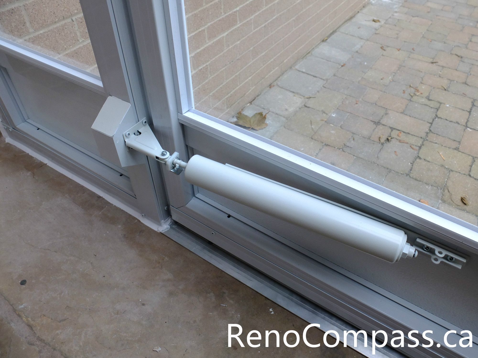 This image shows the door closer mechanism installed on a custom glass storm door at a North York home entrance. The hydraulic door closer ensures smooth and controlled closing, preventing the door from slamming while improving durability and daily usability. Combined with the aluminum frame and full glass panels, the storm door enclosure provides added insulation and protection from wind, rain, and snow. Installed by an experienced Toronto renovation team, this entrance upgrade enhances both practicality and long-term performance for the homeowner.