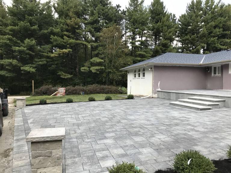 Toronto landscaping renovation featuring a spacious backyard interlock patio designed for outdoor living and entertaining. The durable paving stones, clean edges, and elevated step design create a modern and low-maintenance outdoor space that enhances both functionality and landscape aesthetics for a Toronto residential property.