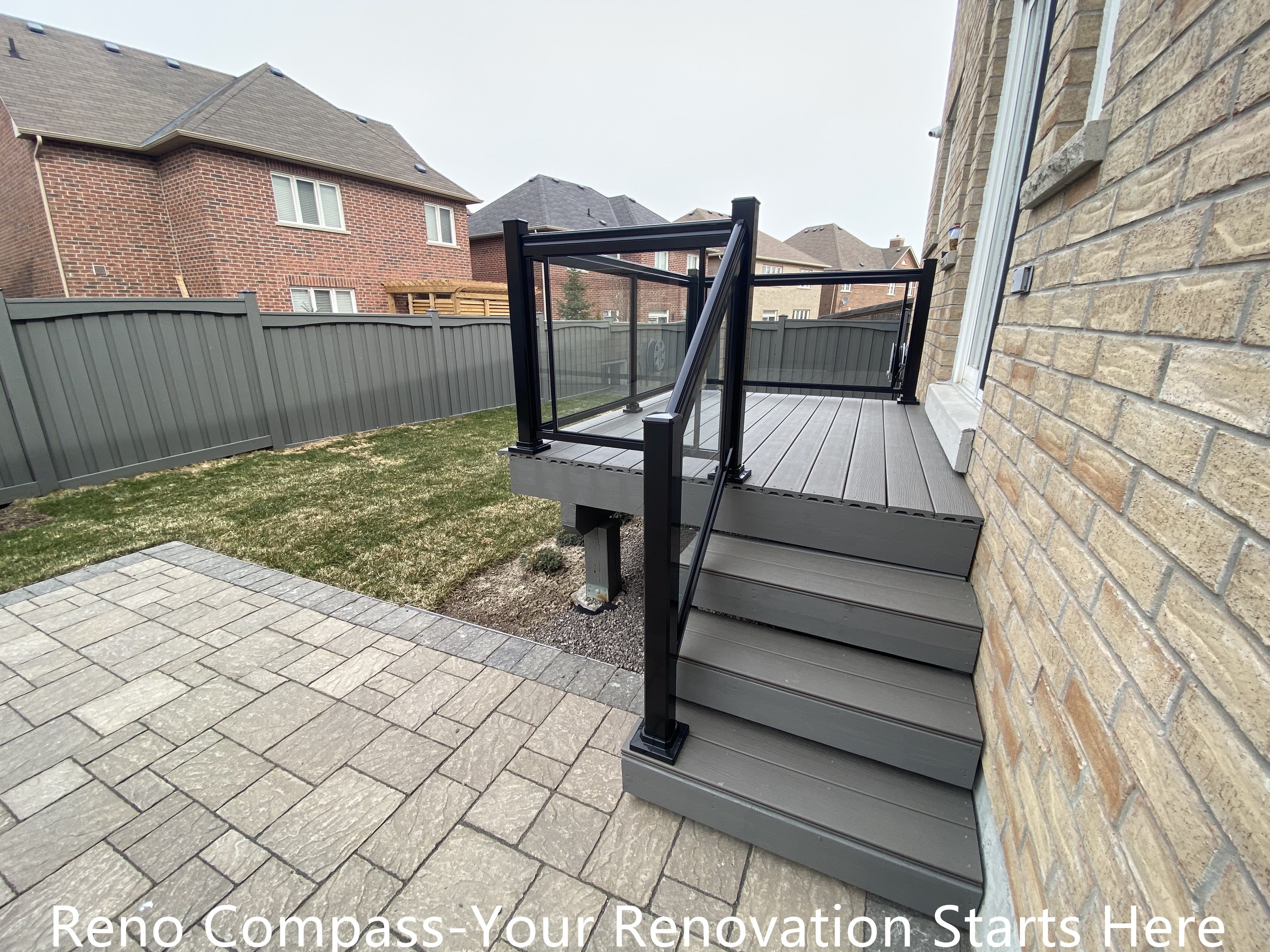 Backyard deck stairs and interlocking patio renovation in Newmarket featuring composite deck steps, black aluminum railing, and seamless connection to the paved outdoor surface. The design improves safety, accessibility, and outdoor flow while maintaining a clean and modern aesthetic. Completed by a professional Toronto renovation company with a focus on durability and precise construction.