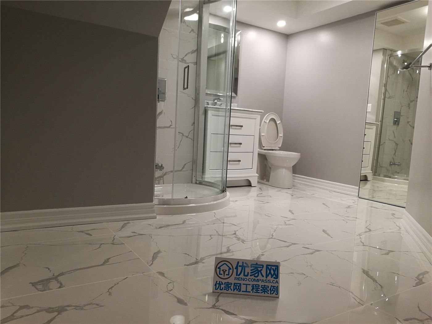 This bathroom shower renovation in New market combines elegant marble-pattern wall tiles with smaller accent tiles to create a visually balanced design. The contrast between the large marble surface and the decorative small tiles adds texture and depth while defining different areas of the shower space.