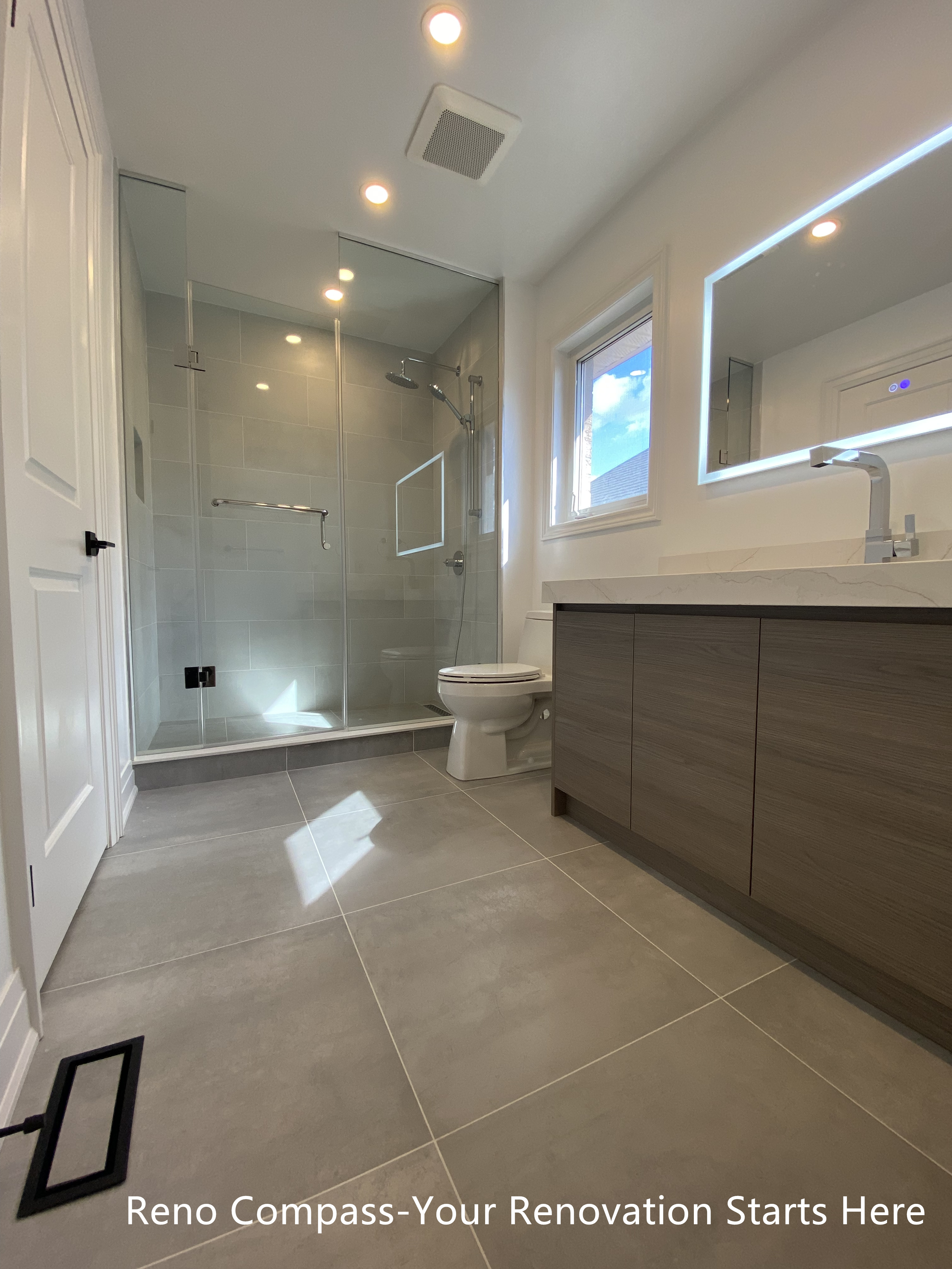 Compact bathroom vanity design in an Oakville interior renovation, showcasing efficient layout, floating wood-finish cabinetry, and contemporary lighting. This renovation focuses on maximizing space while maintaining a clean, modern aesthetic completed by a professional Toronto renovation company.