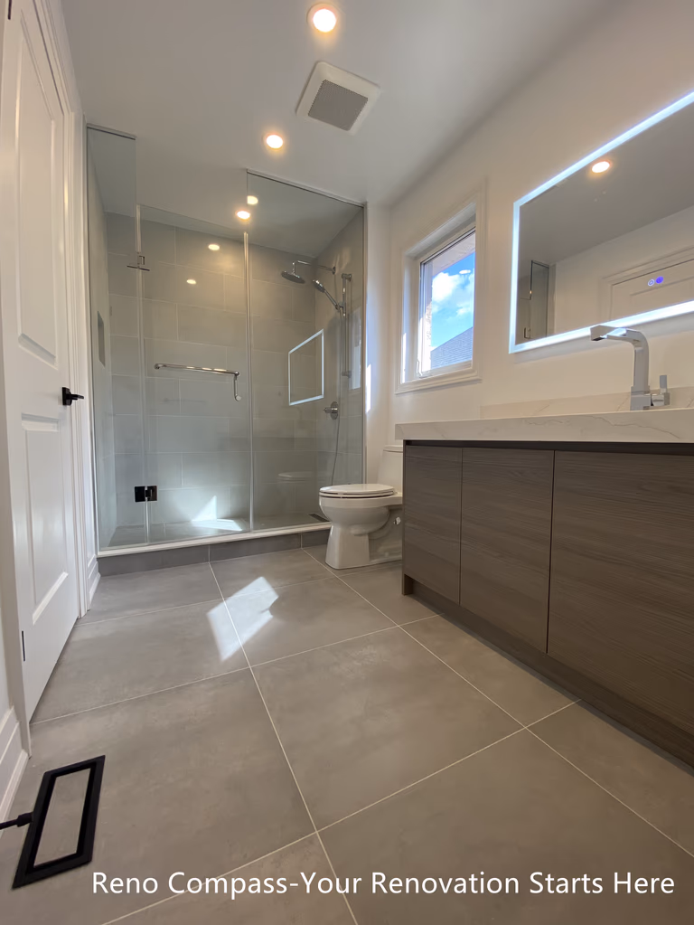 Compact bathroom vanity design in an Oakville interior renovation, showcasing efficient layout, floating wood-finish cabinetry, and contemporary lighting. This renovation focuses on maximizing space while maintaining a clean, modern aesthetic completed by a professional Toronto renovation company.