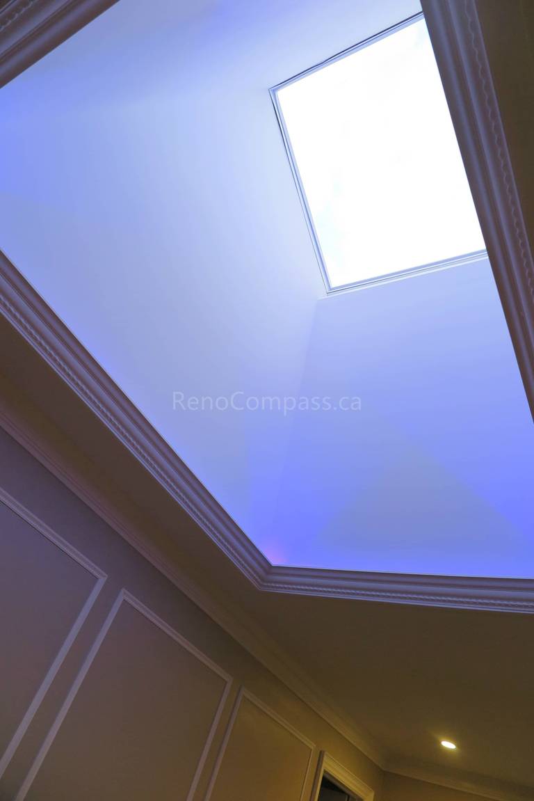 This Markham interior renovation features a custom tray ceiling design with integrated ambient lighting and a central skylight that enhances natural brightness throughout the space. Detailed crown molding and wall panel finishes add architectural elegance, creating a refined and modern interior atmosphere. Completed by Reno Compass, a trusted renovation contractor specializing in custom ceiling design and full home interior renovations across Markham and the Greater Toronto Area.