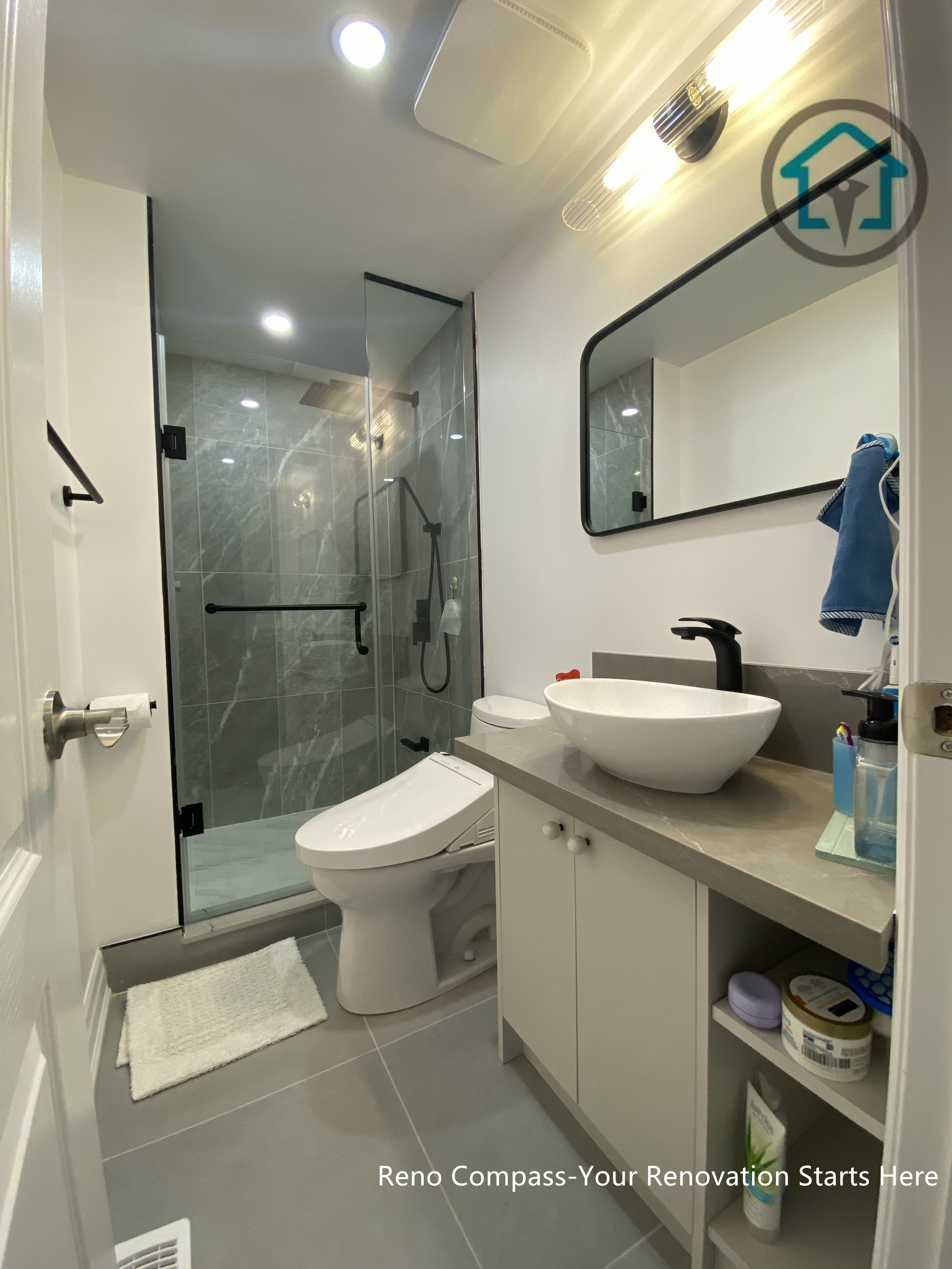 This compact bathroom renovation in Toronto demonstrates how thoughtful layout planning can maximize both comfort and functionality in a limited footprint. The design features a frameless glass shower enclosure with large-format wall tiles, creating a visually open and seamless look. A floating-style vanity with integrated storage, vessel sink, and matte black fixtures adds a modern touch while maintaining practicality. Neutral finishes, recessed lighting, and clean sightlines help the space feel bright, efficient, and well-balanced for everyday use.