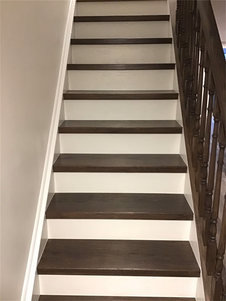 Custom-built wood staircase with dark-stained handrails and spindles completed in this Richmond Hill basement renovation. The upgraded stair system enhances safety, durability, and visual appeal while seamlessly matching the modern vinyl plank flooring throughout the finished basement.