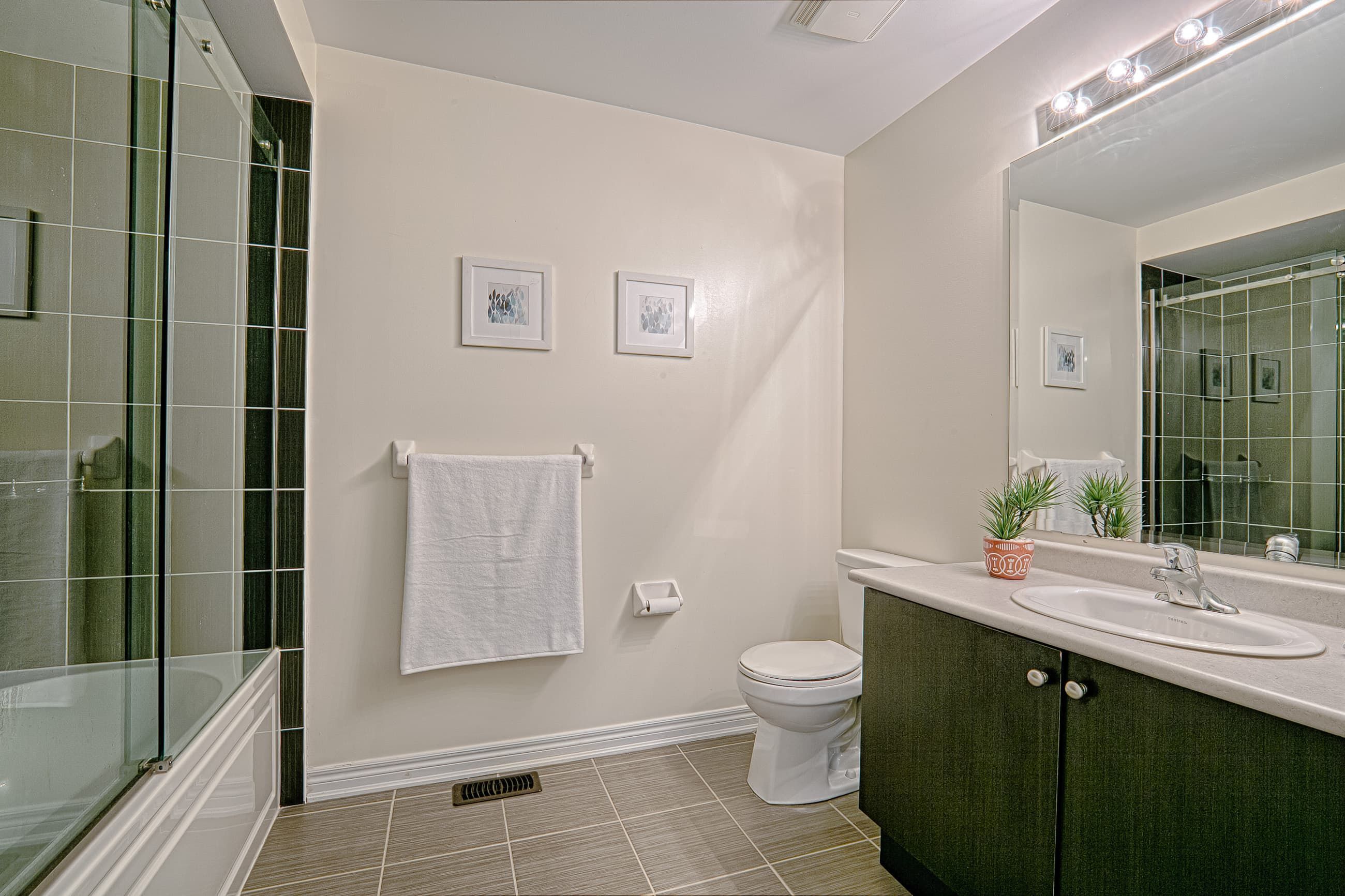 This contemporary bathroom renovation features a sleek glass-enclosed shower, modern vanity with ample storage, and a large mirror with bright overhead lighting to enhance the sense of space. Neutral wall tones and durable floor tiles create a clean and timeless design suitable for everyday living. Designed with both comfort and functionality in mind, this bathroom upgrade reflects the quality workmanship of a trusted Toronto renovation company specializing in complete residential interior renovation and modern home improvements.