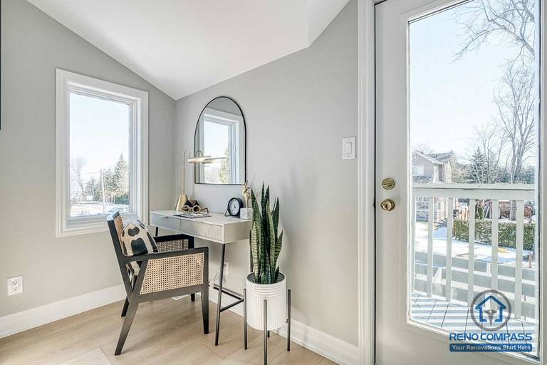 This Georgian interior renovation features a bright bedroom vanity corner with clean lines, a compact desk setup, and natural light from adjacent windows and balcony door. The thoughtful layout enhances both function and comfort, completed by a Toronto renovation company.