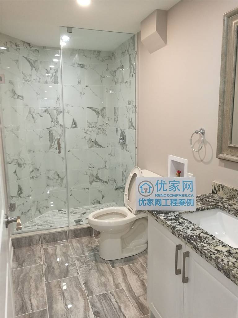 This image features a newly completed Richmond Hill basement bathroom renovation, highlighting a modern glass-enclosed shower with marble-look wall tiles, upgraded floor tiling, and a sleek vanity with stone countertop. The bathroom design maximizes space and functionality while maintaining a clean, contemporary aesthetic. This basement bathroom remodel was completed by an experienced Toronto renovation company, providing high-quality renovation solutions for Richmond Hill homeowners.