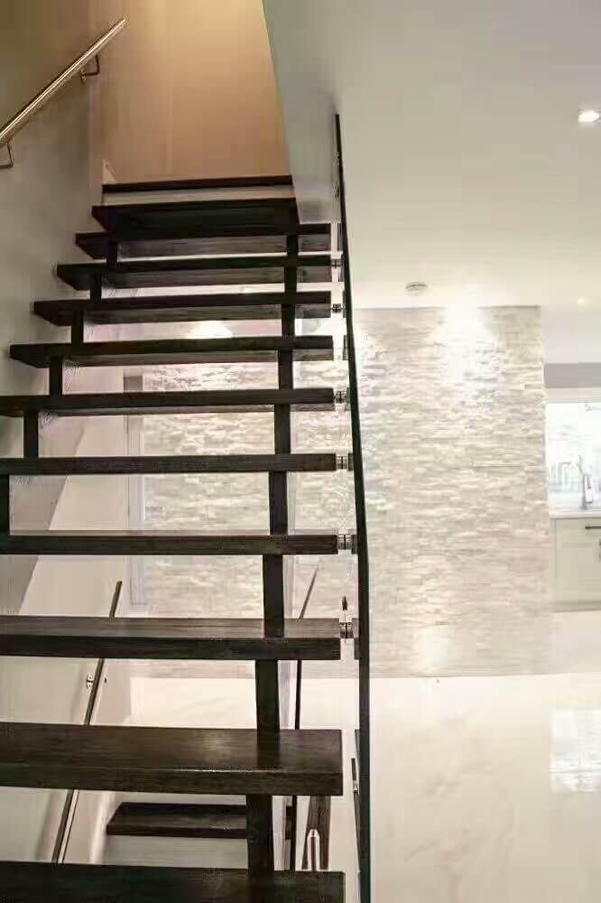 This Markham interior renovation features a modern floating wood staircase with open risers and sleek glass railing, creating a clean and contemporary focal point. The dark wood treads contrast beautifully with light marble-look flooring and textured feature walls, enhancing the home’s modern aesthetic. Designed to improve visual openness and natural light flow, this staircase upgrade adds both style and functionality to the space. Completed as part of a high-end Toronto home renovation by a professional renovation contractor.