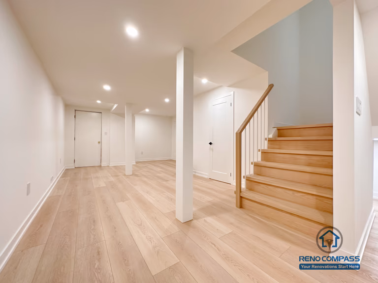 This Markham basement renovation features a clean, open-concept layout with wide-plank flooring, recessed ceiling lights, and a solid wood staircase that creates a seamless connection between levels. Structural columns are carefully integrated to maintain openness while ensuring long-term stability. Designed and completed by a professional Toronto renovation company, this basement space is ideal for a family living area, entertainment zone, or flexible multi-purpose use.