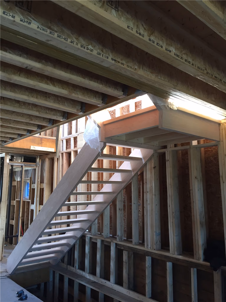 This image shows a newly installed hardwood staircase during a basement renovation project in Toronto. The staircase structure is carefully built with evenly spaced treads and strong side framing to ensure safety, durability, and proper access between levels. Installed within a framed construction environment, this stair system demonstrates precise carpentry and structural planning. As a professional Toronto Renovation Company, Reno Compass Inc. provides high-quality staircase installation and renovation services for residential projects across Toronto and the Greater Toronto Area.
