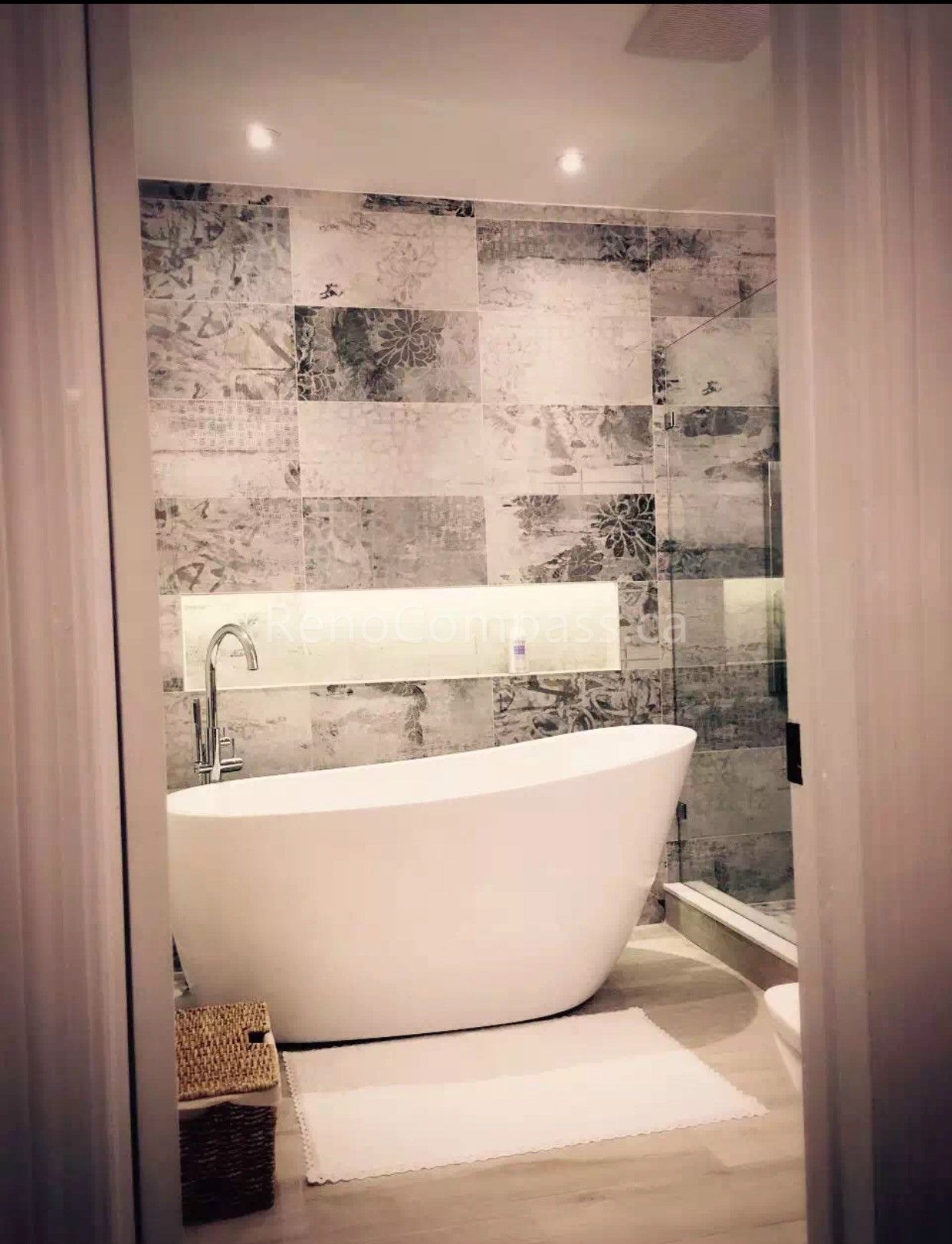 A modern bathroom interior renovation in Toronto featuring a freestanding soaking bathtub, textured tile accent wall, recessed lighting, and warm wood flooring. This interior design emphasizes clean lines, spa-inspired comfort, and contemporary finishes, showcasing professional Toronto interior design and renovation craftsmanship.