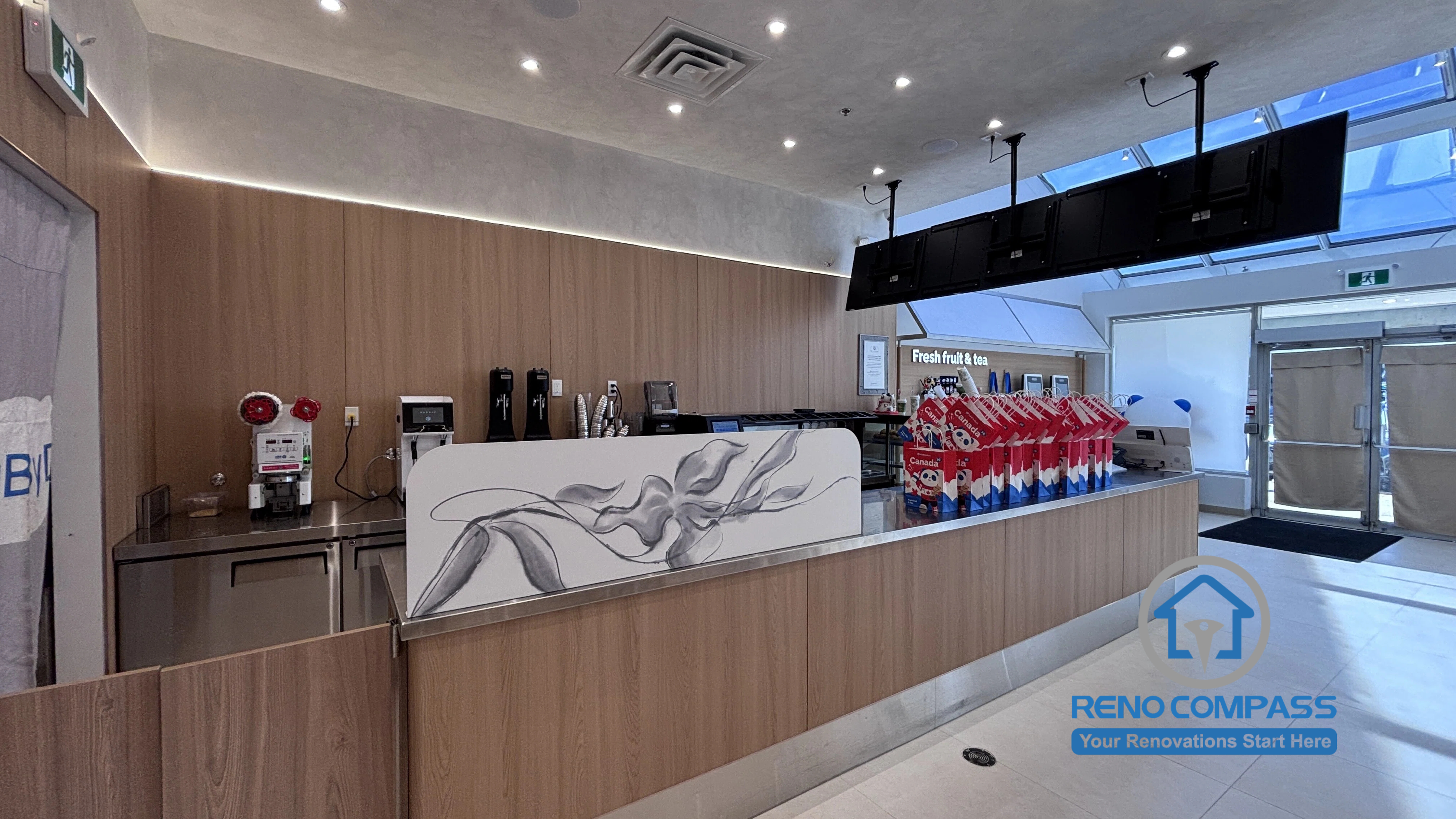 Completed TEABYDO bubble tea shop renovation in Richmond Hill featuring a custom commercial front counter, modern wood wall finishes, integrated LED lighting, beverage preparation area, digital menu display system, and clean minimalist café interior design. Commercial renovation project completed by Reno Compass serving Richmond Hill, Toronto, and the GTA.