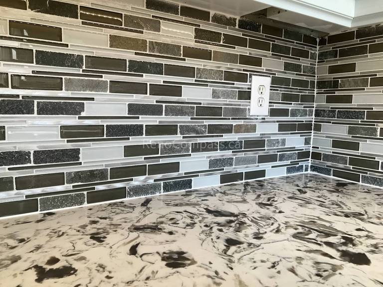 Light grey shaker-style kitchen cabinets with decorative glass mullion doors surrounding a large window in a Toronto home.