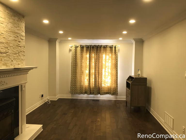 This Mississauga interior renovation highlights a bright bay window living space enhanced with custom curtain installation, detailed trim work, and rich hardwood flooring. The upgraded windows improve natural light control while adding warmth and elegance to the room. Completed by a trusted Toronto renovation company, Reno Compass Inc., this project showcases refined interior finishing and professional craftsmanship.
