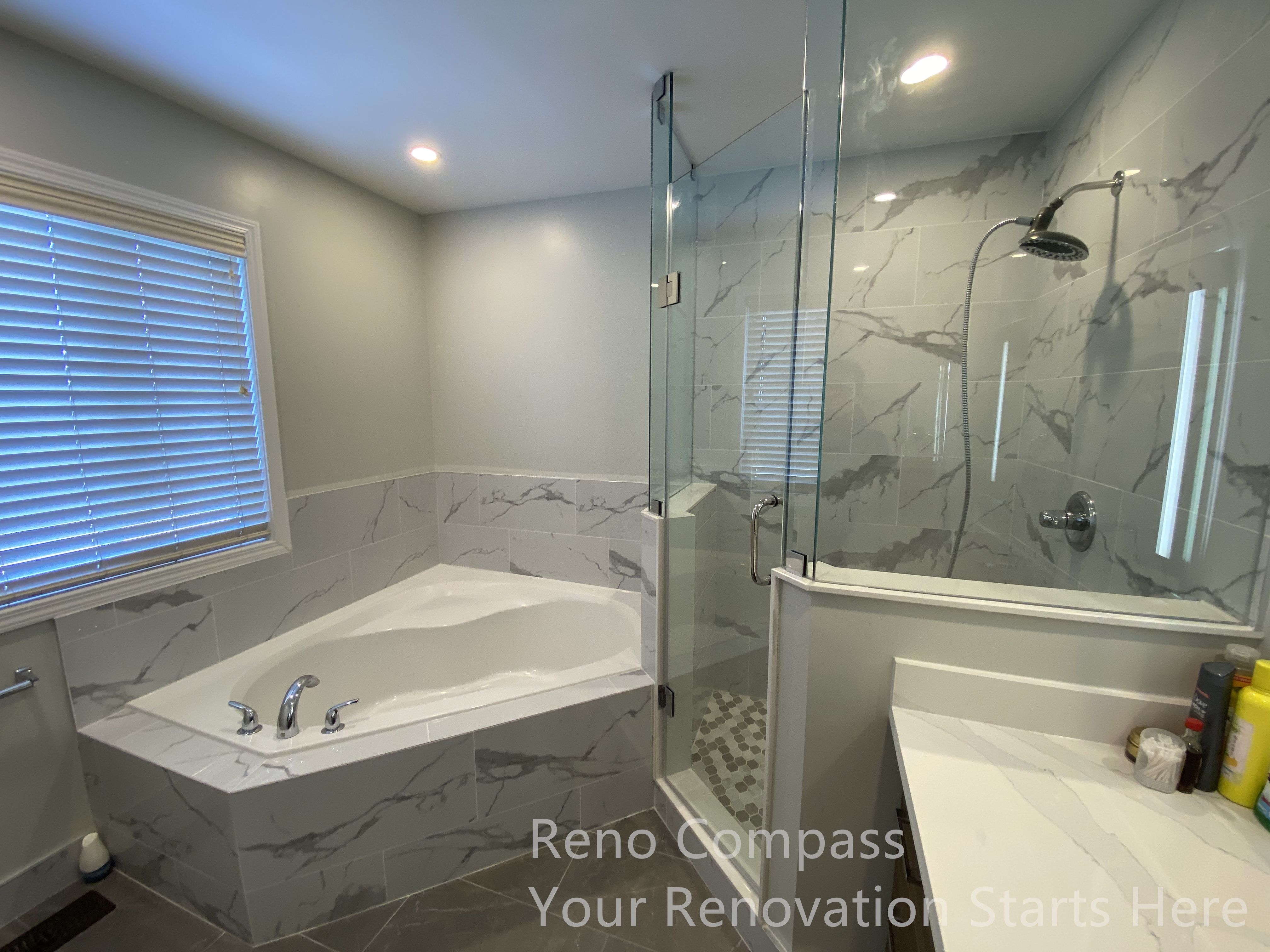 This Newmarket bathroom renovation features a thoughtfully designed layout combining a built-in bathtub and a frameless glass shower enclosure. Marble-look wall tiles extend around the tub and shower area, creating visual continuity while enhancing durability and moisture resistance. The glass shower enclosure maintains openness and allows natural and artificial light to circulate throughout the space. Clean-lined fixtures and a streamlined vanity surface contribute to a calm, spa-inspired atmosphere that balances everyday functionality with modern design. This bathroom renovation was completed by Reno Compass, serving homeowners in Newmarket and across the GTA.