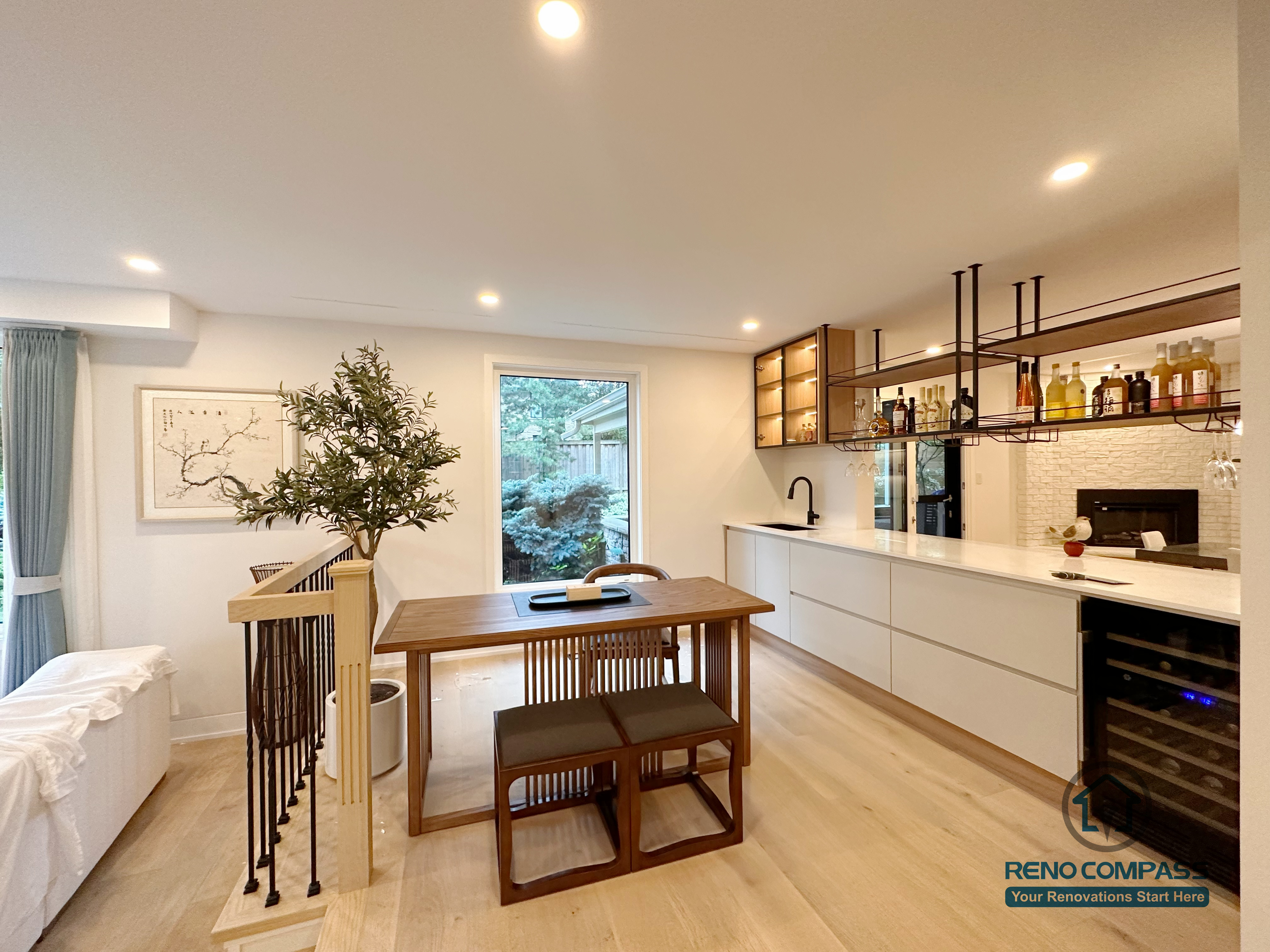 An open-concept kitchen and dining area renovation in Toronto featuring custom cabinetry, a built-in bar and beverage station, and clean-lined storage design. Warm wood flooring, integrated lighting, and seamless circulation create a functional yet elegant living space, completed by a professional Toronto renovation company.